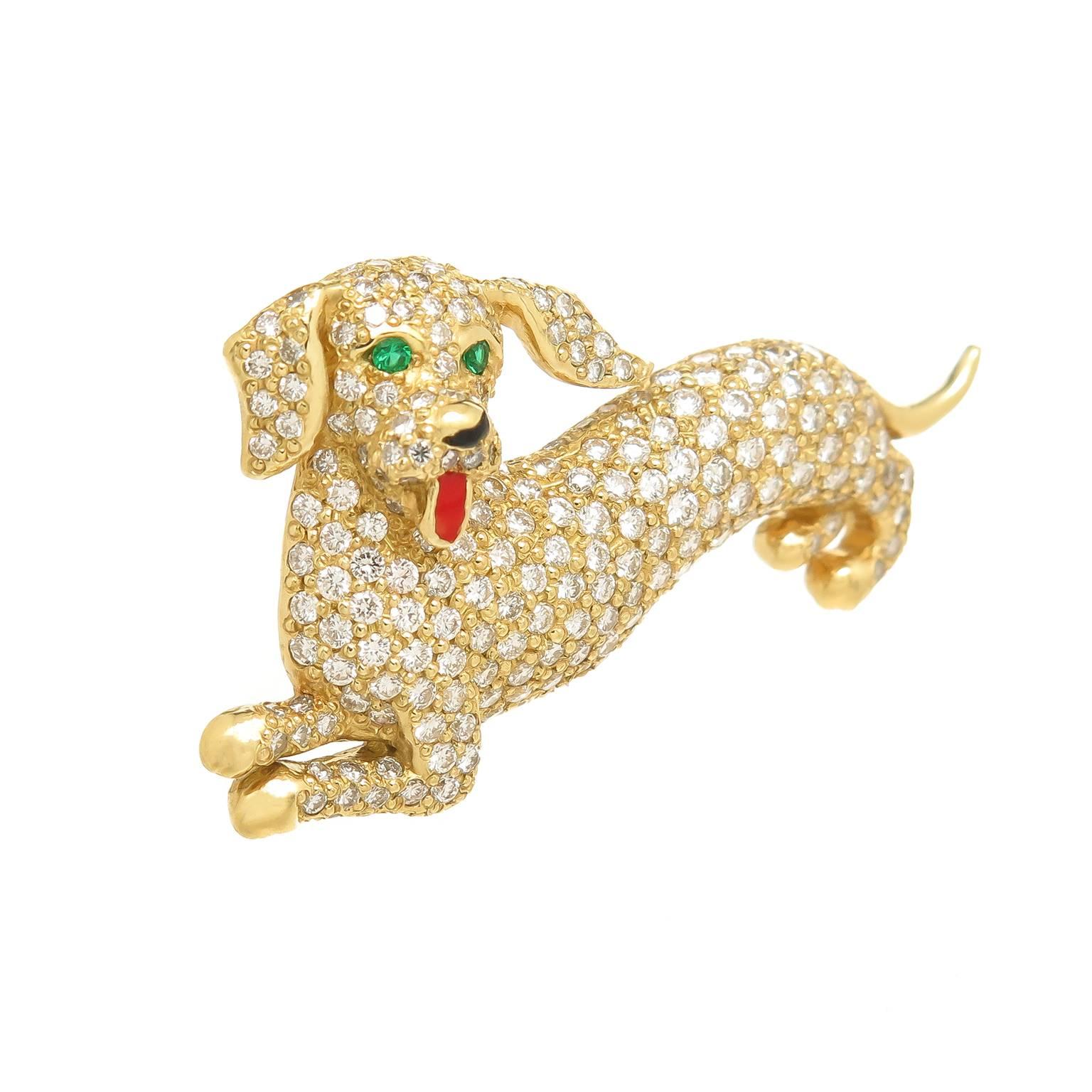 Circa 1980 18K Yellow Gold Whimsical puppy dog brooch, measuring 1 3/4 inch in length and set with Fine White, round Brilliant cut Diamonds totaling 2.50 carat and further detailed with Emerald eyes and a red enamel tongue. 