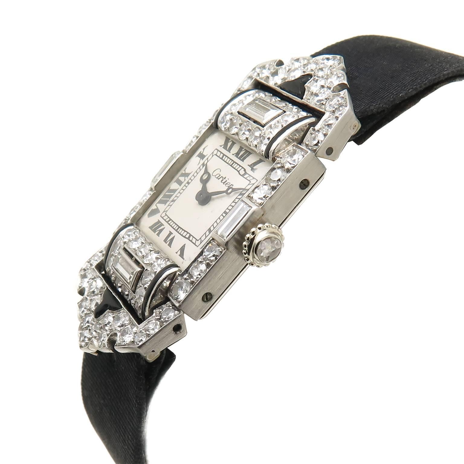 1920s Cartier Platinum, Diamond and Onyx Wrist Watch, measuring 1 5/8 inch in length and 3/4 inch wide, set with round and Baguette Diamonds totaling approximately 2 carats and a Diamond Set Crown. Mechanical, manual wind EWCC, European Watch &