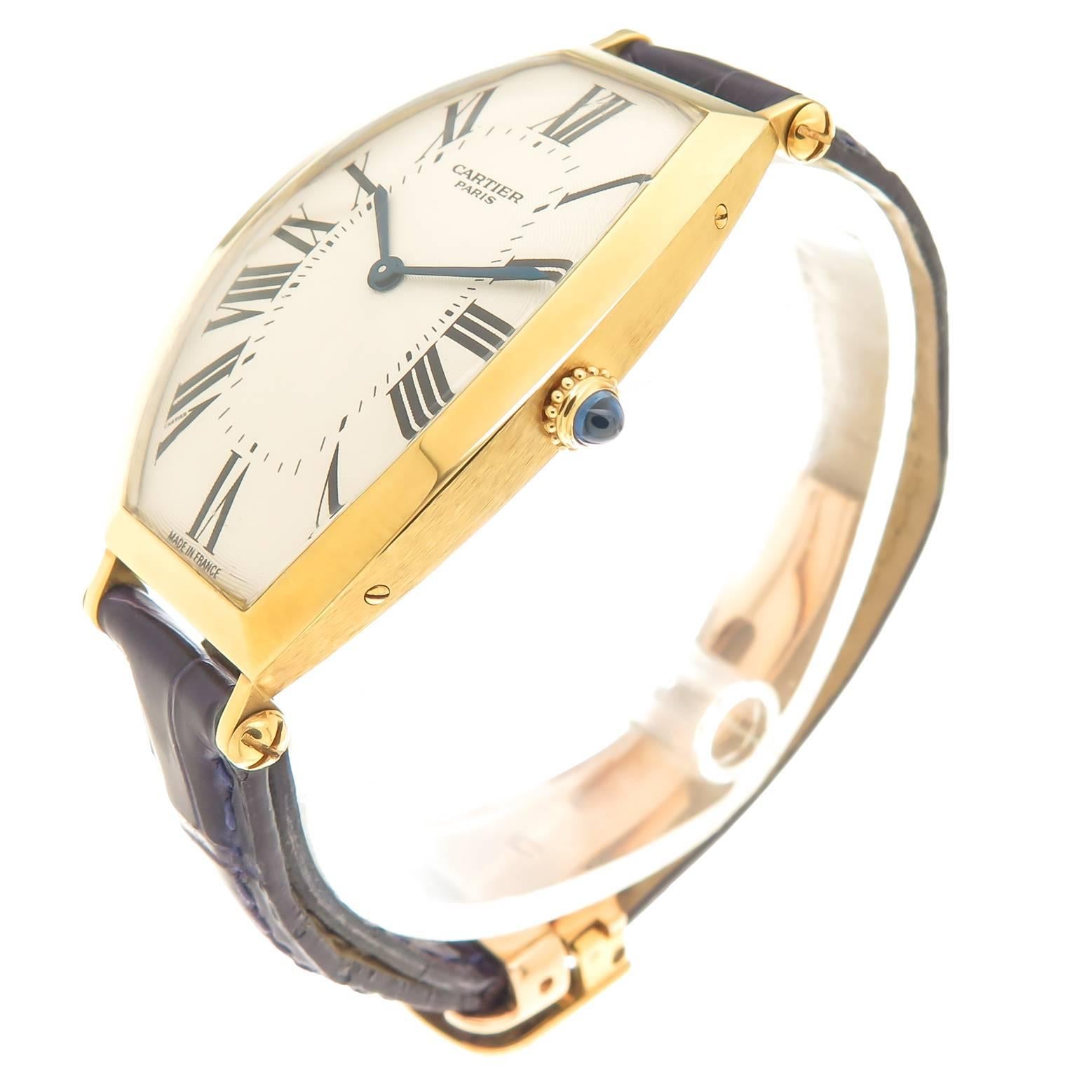 Circa 2000 Cartier Tonneau Wrist watch, 18K Yellow Gold Water resistant case measuring 45 X 25 MM. Mechanical, manual wind movement. Silvered, engine turned, Guilloche dial with Black Roman Numerals and a Sapphire crown. Original Cartier Purple