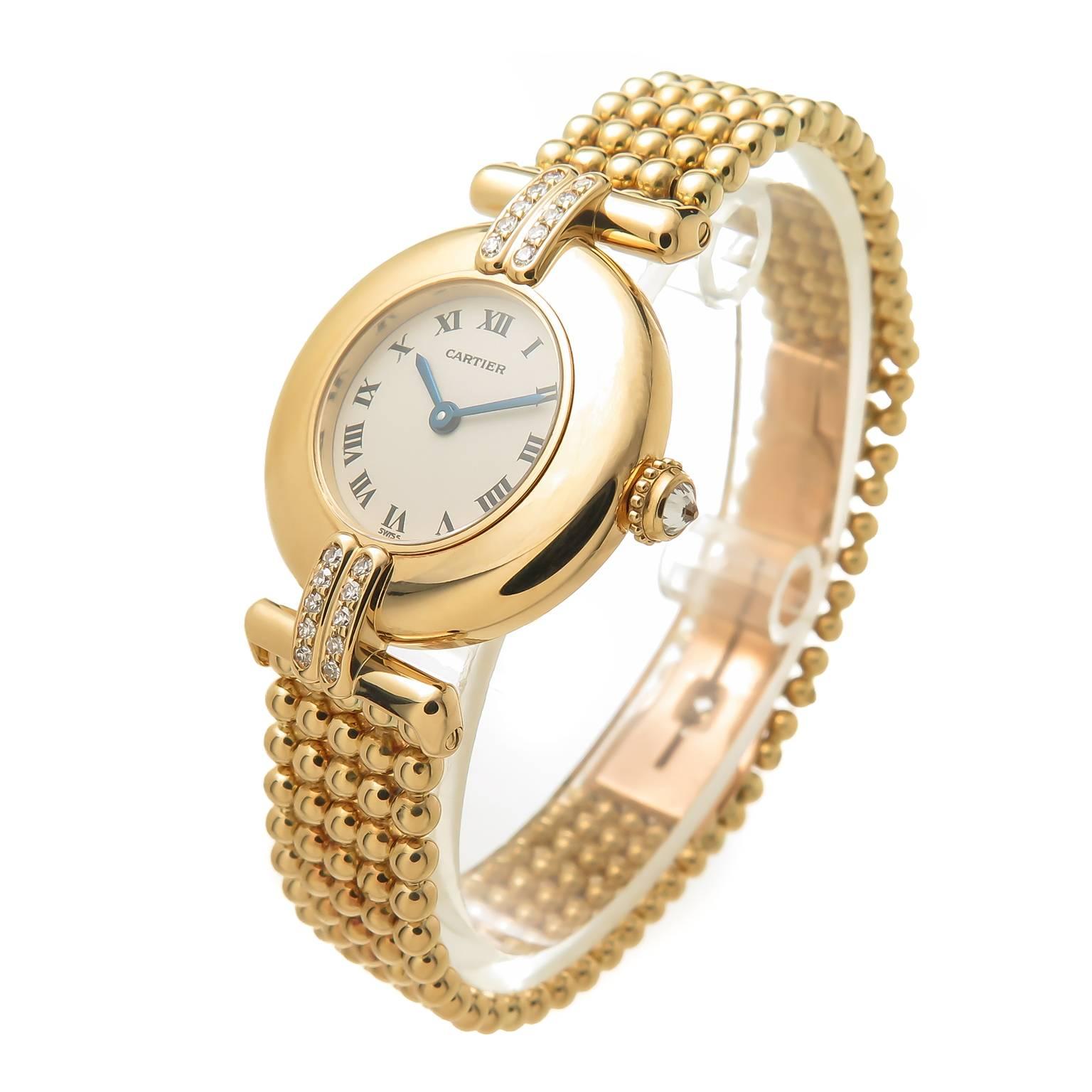 Circa 2000 Cartier Rivoli Collection 18K Yellow Gold ladies Wrist Watch, 24 MM Water Resistant case, Quartz Movement, White Dial with Black Roman Numerals, 2 rows of Round Brilliant cut Diamonds on either side of the case and a diamond set crown.