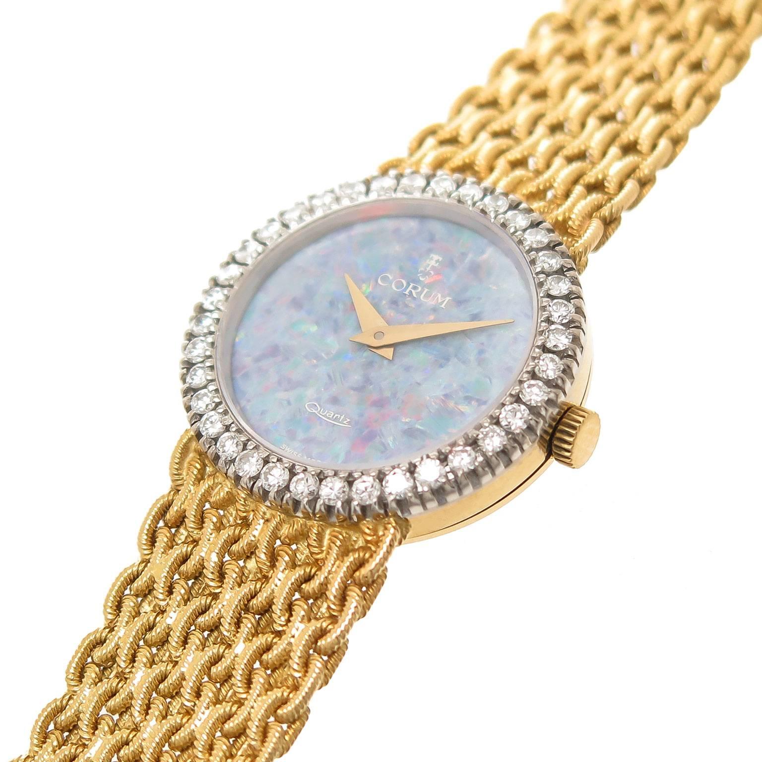 Circa 1980s Corum 18K Yellow Gold Ladies Watch, 24 MM diameter case with a White Gold bezel set with round Brilliant cut Diamonds totaling .70 Carat, quartz movement, Fire Opal face with yellow Gold hands. Woven link Corum Bracelet measuring 5/8