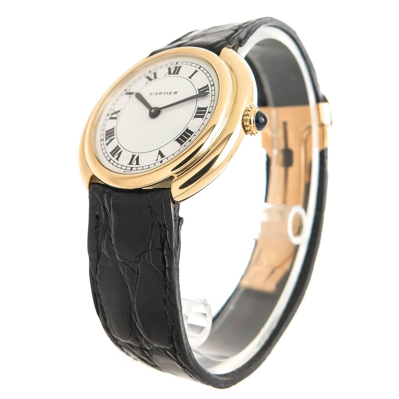 Circa 1960s Cartier 18K Yellow Gold Round Cintree Wrist watch, 33 MM Stepped, water resistant case. Manual wind, Mechanical Movement, White Dial with Black Roman Numerals. Black Croco strap with Original Cartier 18K Yellow Gold Deployment buckle.