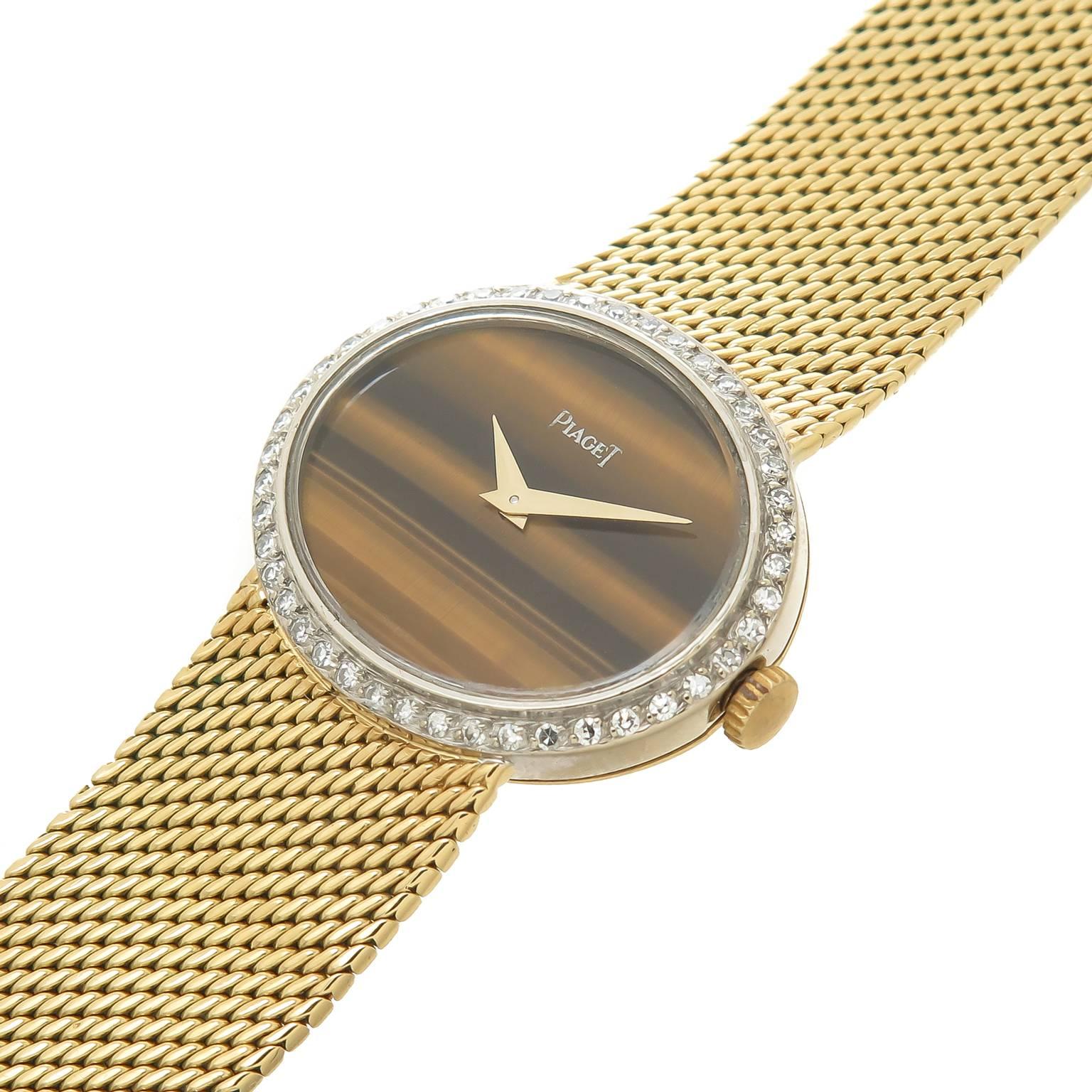 Circa 1980 Piaget Ladies Wrist Watch,  25 X 21 MM Water Resistant Case with Factory Diamond Bezel of approximately 1 Carat. Manual wind Mechanical movement, Tiger Eye Dial with Gold Hands. 5/8 inch wide Soft mesh link Piaget bracelet with Piaget