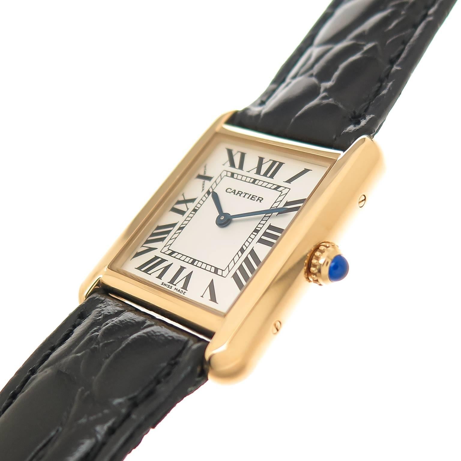 Circa 2012 Cartier Classic Tank wrist Watch from the Tank Solo Collection, 30.5 X 24 MM 18K Yellow Gold Water Resistant case with Steel Back. Quartz Movement,  Silvered Dial with Black Roman numerals, scratch resistant crystal and a blue Spinel