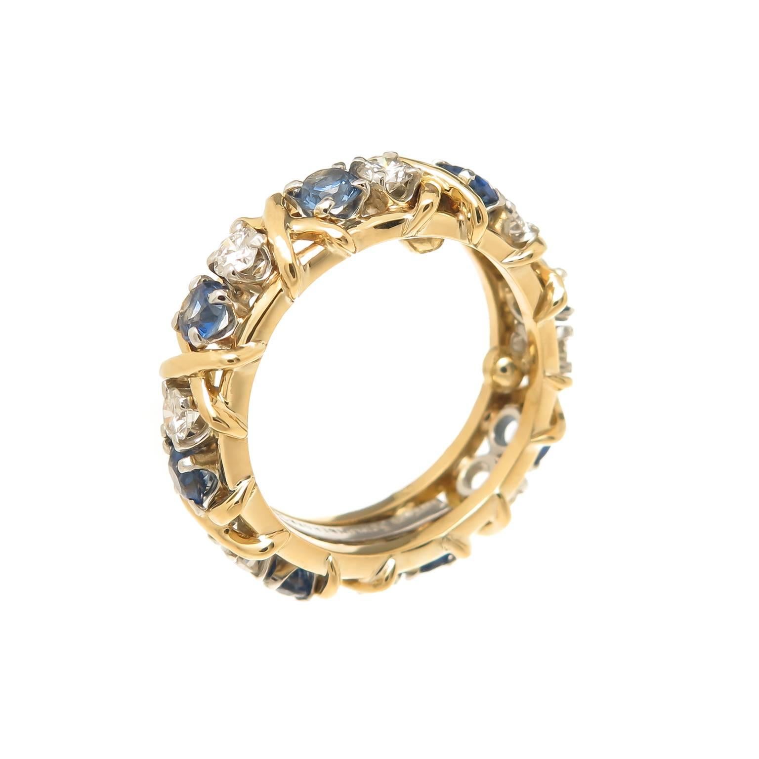 Circa 2000 Jean Schlumber for Tiffany & Company Platinum and 18K yellow Gold Classic X Band Ring. Set with 8  Round Brilliant cut Diamonds and 8 round Sapphires. Measuring 4.5 MM wide. Finger size = 5 1/2 