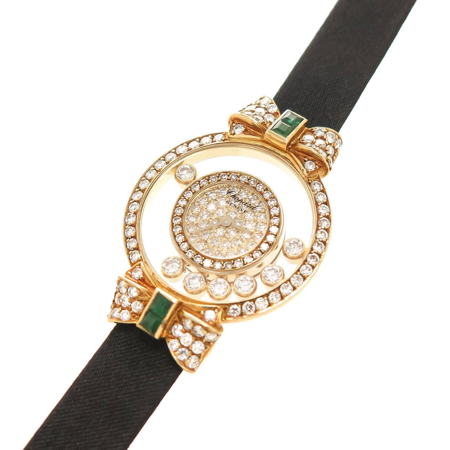 Circa 2005 Happy Diamond Wrist watch, 23 MM 18K yellow Gold case with Bow Tie Lugs, Quartz Movement with back set feature. 7 Floating Diamonds, inner Diamond Bezel, Pave Diamond Face and outer Diamond Bezel with Diamond and Emerald set lugs. Diamond