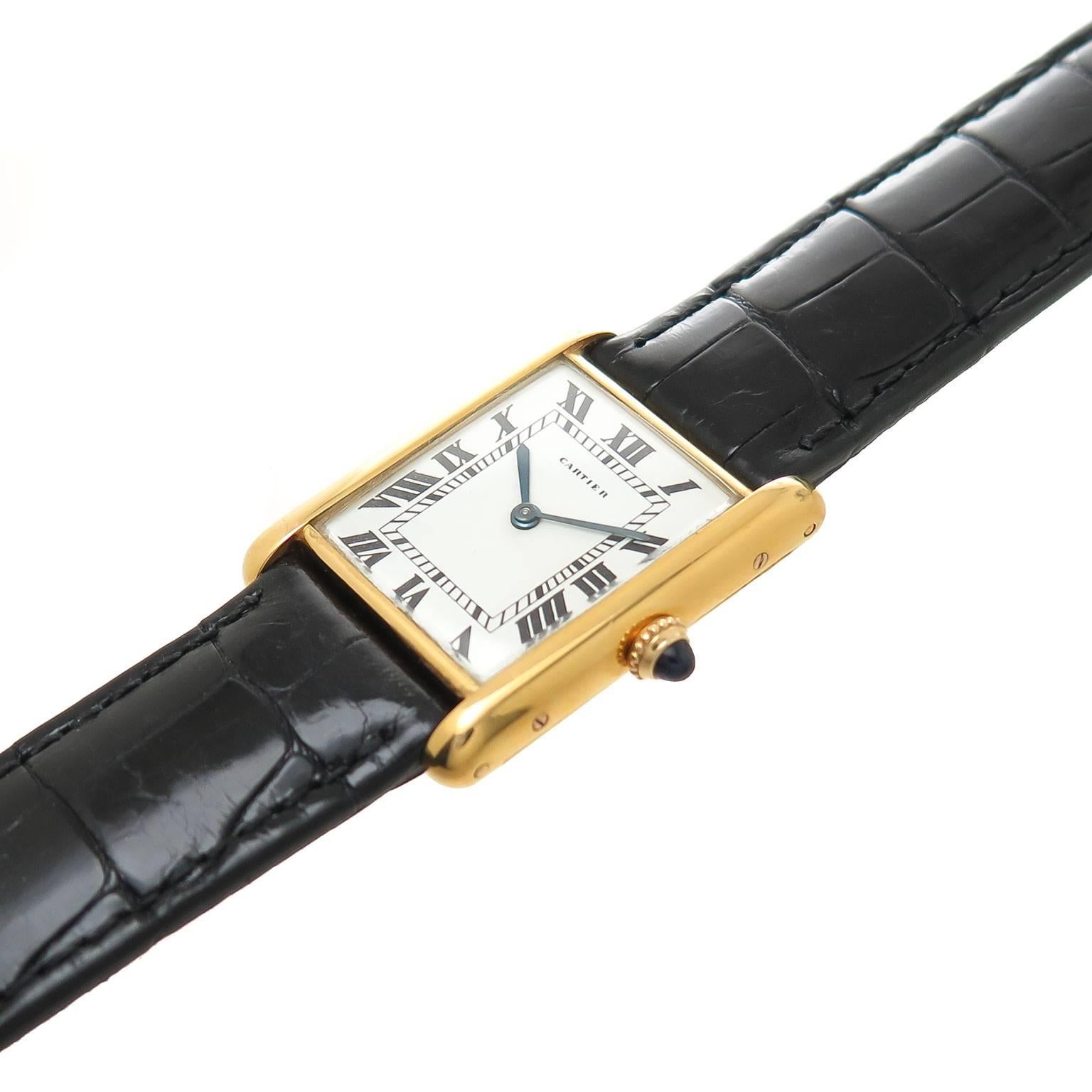 Circa 1980 Cartier Classic Tank wrist watch, 30 X 23 MM 18K yellow Gold Water Resistant case, mechanical, manual wind movement, white Dial with Black roman numerals, Sapphire crown. New, Black Padded Alligator Strap with Cartier Gold Plated Tang