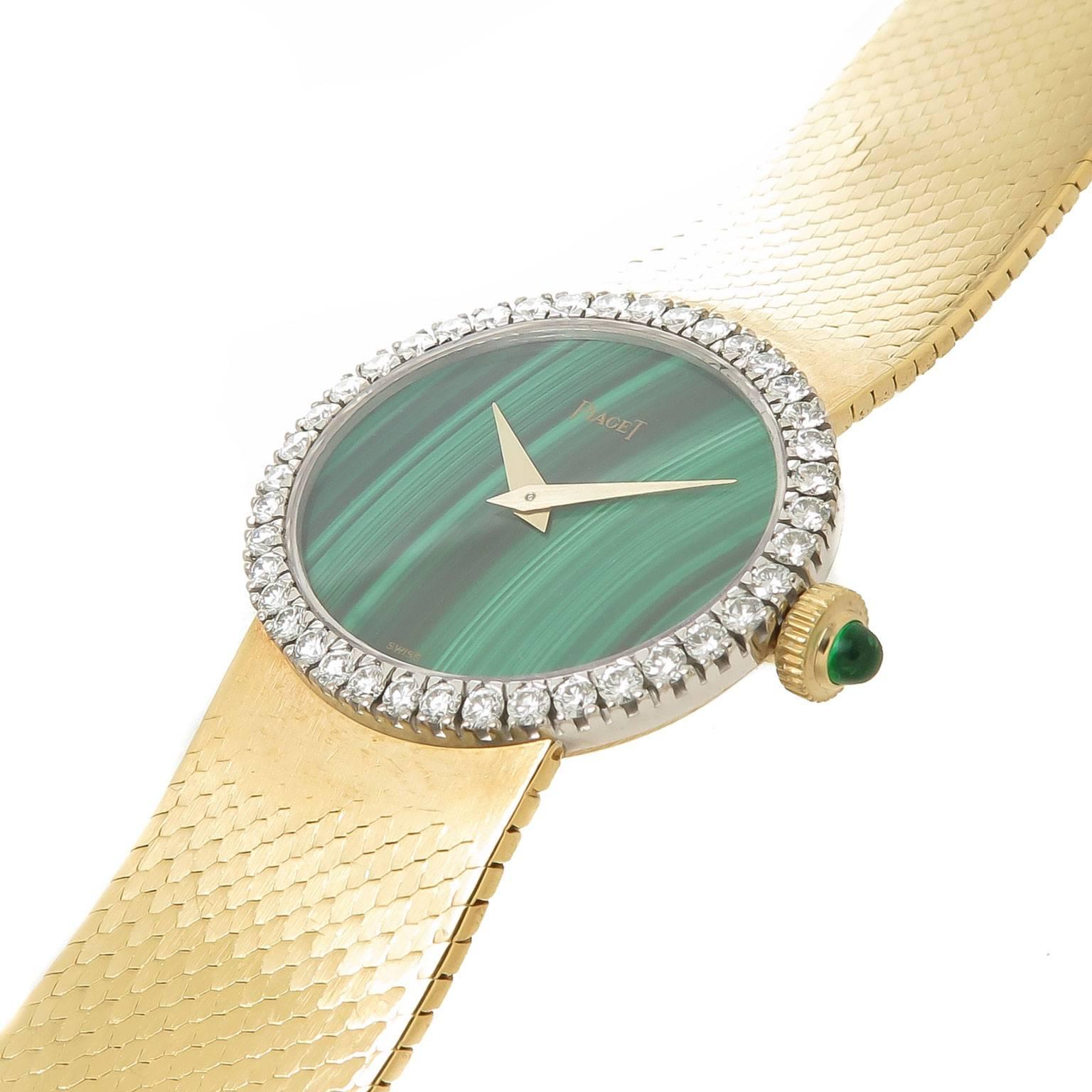 Circa 1970s Piaget, 27 X 24 MM 18K yellow Gold Oval case, with a Factory Diamond set Bezel of Round Brilliant cut Stones that weigh a total 1 of Carat. 17 Jewel Manual wind, mechanical movement. Malachite stone Dial With gold hands and an Emerald