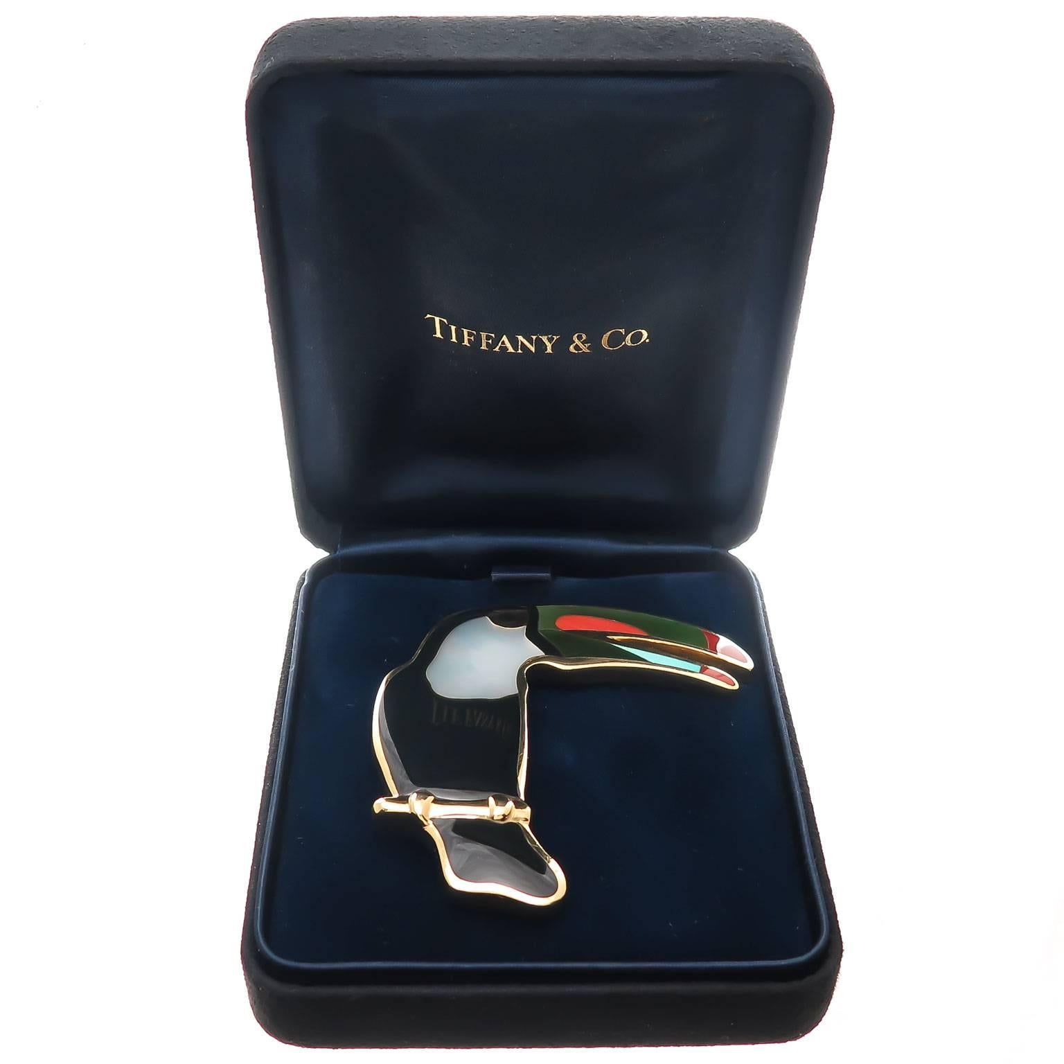 Circa 1980 Tiffany & Company 18K Yellow Gold Toucan Bird Brooch, measuring 2 1/2 inch in height and 2 1/2 inch in width. Inlaid with Mother of Pearl, Onyx, Coral, Turquoise and Jade. Nice heavy solid construction with a double clip pin. Comes in