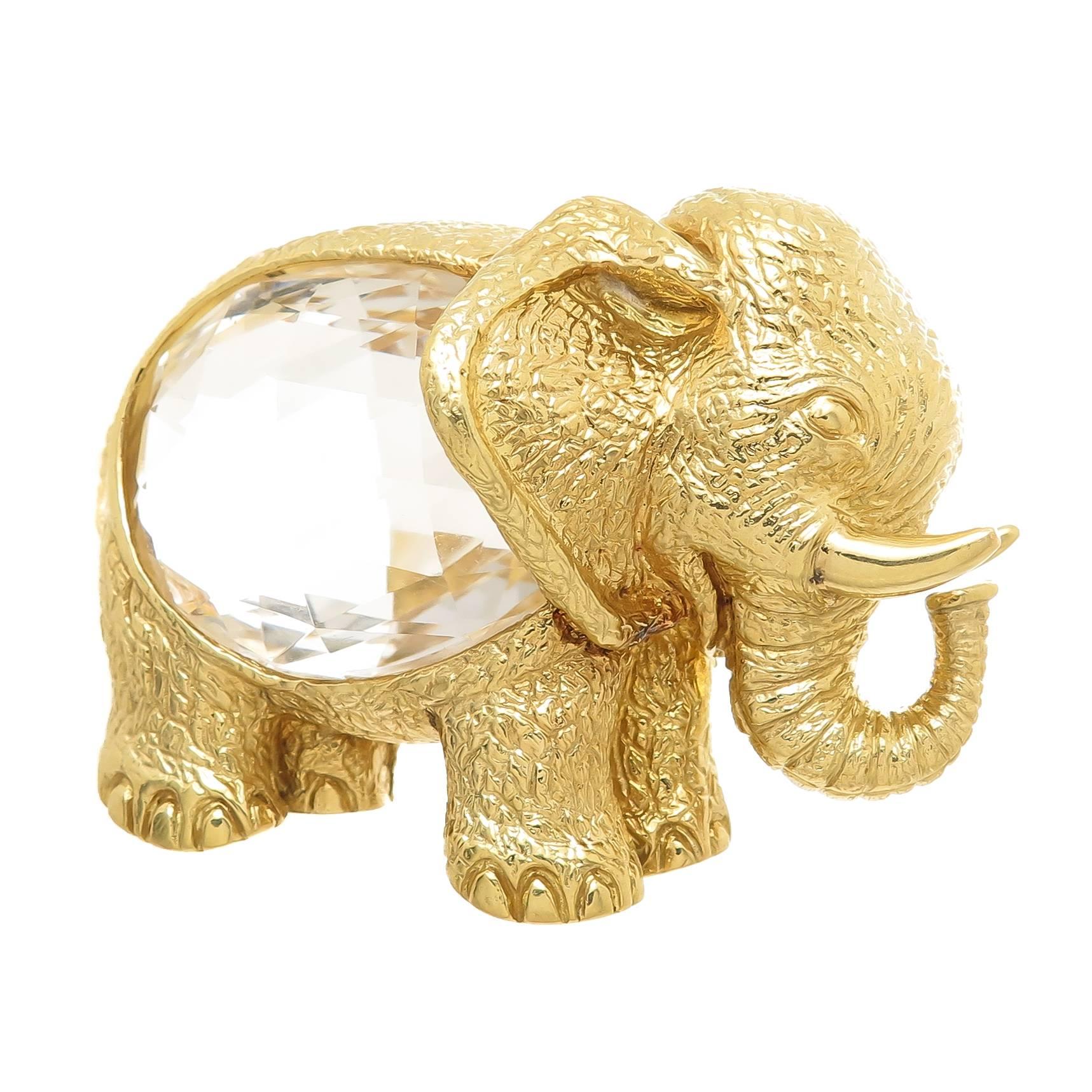 Circa 1990 David Webb 18K Yellow Gold Elephant Brooch, measuring 2 1/2 inch in length and 2 inch in height this piece of wearable sculpture is very detailed on all sides and weighs a total of 86.5 Grams. The center is set with a two sided faceted