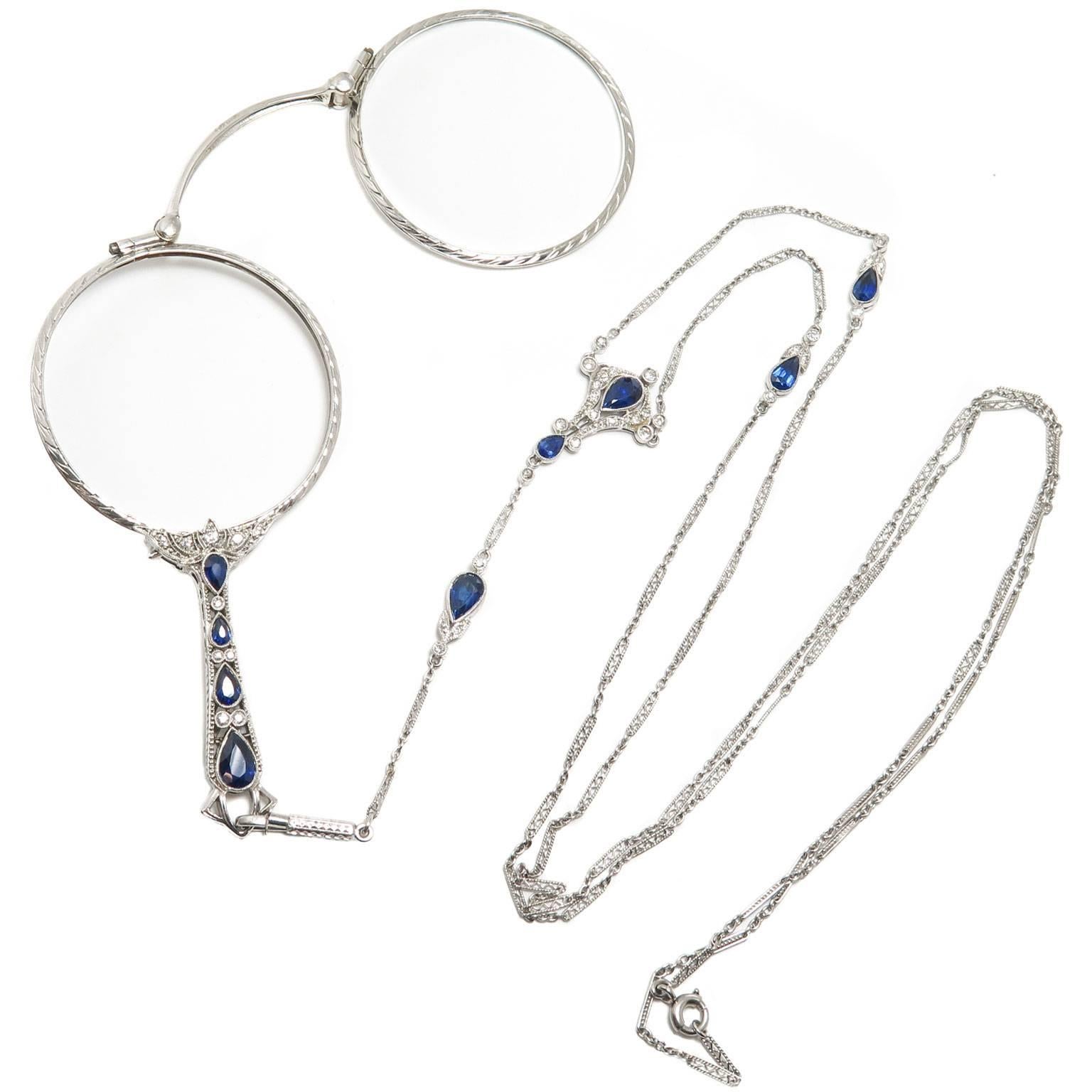 Circa 1920s Cartier Lorgnette with matching chain, the lorgnette measures 3 inch in length, is set with Diamonds and Sapphires and is further finished with hand engraved design work. Recently fitted with Clear lenses. The matching chain measures 33