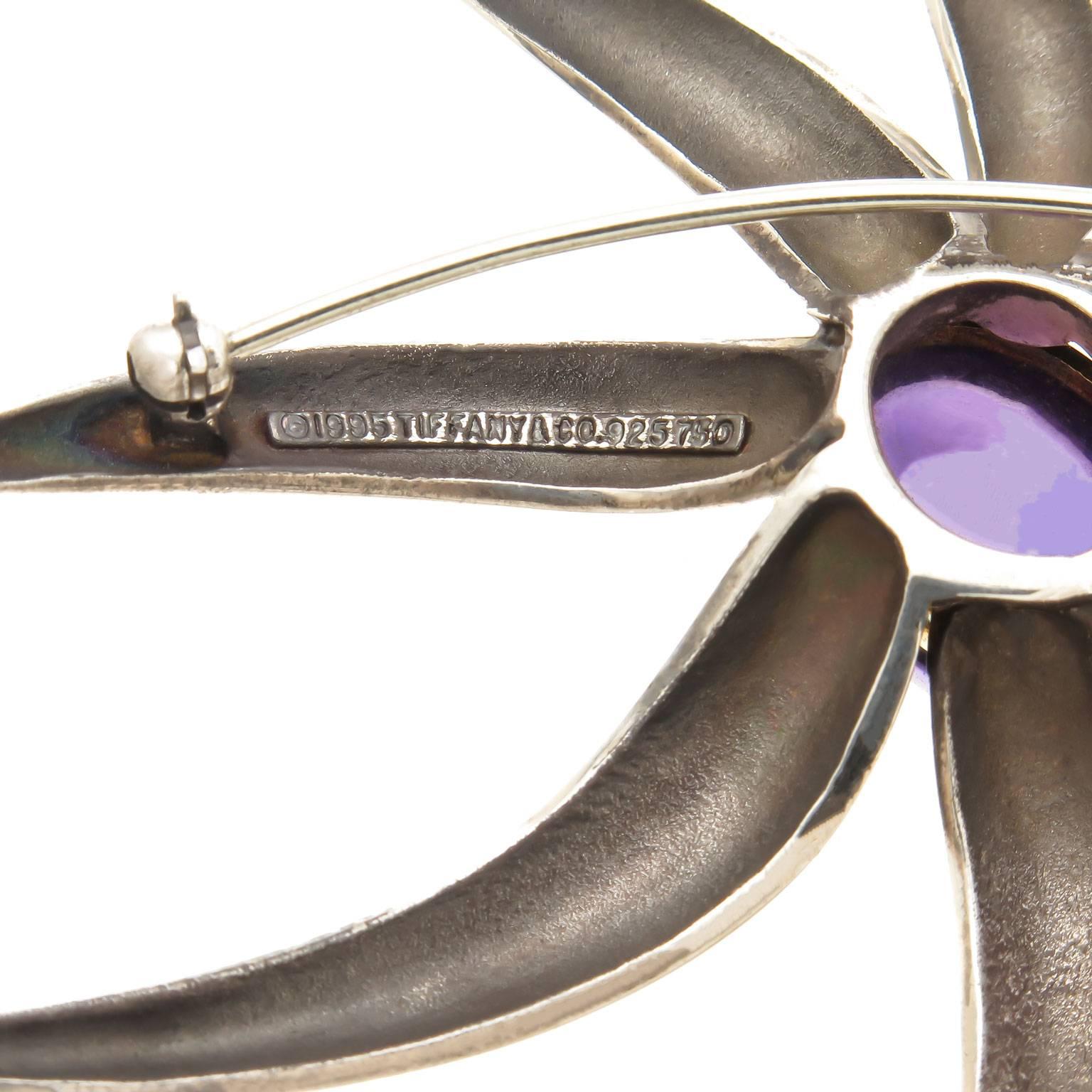 Circa 1990s Tiffany & Co Sterling Silver and 18k yellow Gold Fireworks collection Brooch. Measuring 3 X 2 1/2 inch and centrally set with a cabochon Amethyst measuring 1/2 X 3/8 inch, approximately 4 Carats. 