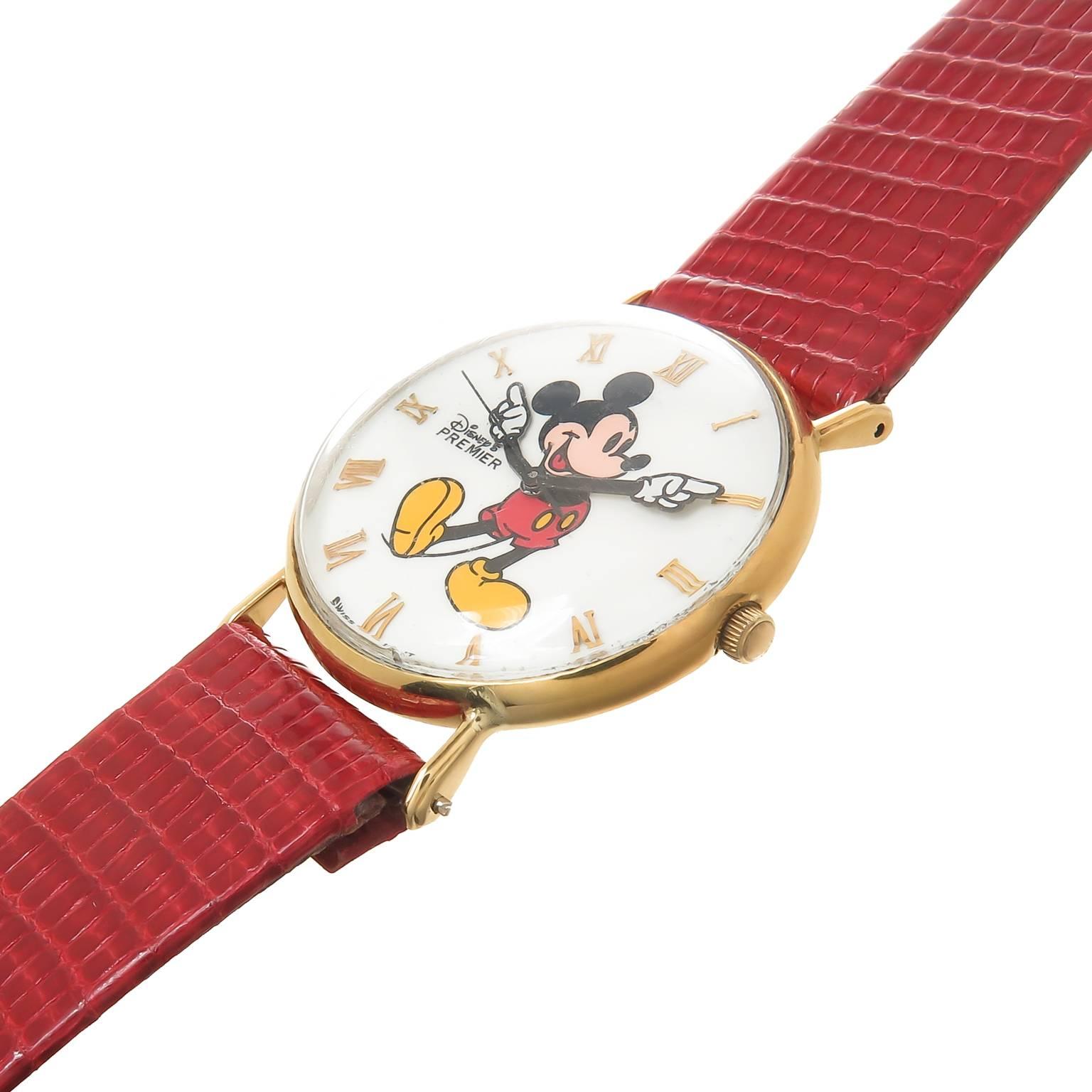 Circa 1990s  Disney Premier,  Mickey Mouse Wrist watch, 32 MM 18K yellow Gold case. Swiss Quartz Movement, Bright color Mickey Mouse on the dial with raised Gold markers, animated hands and a sweep seconds Hand. New Red Lizard Strap. Total length 8