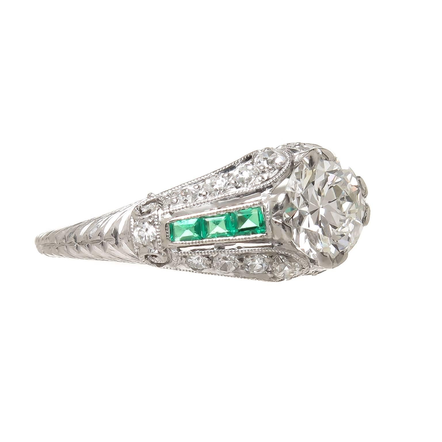 Circa 1920s Platinum and Diamond Engagement in absolutely mint almost unworn condition. Centrally set with a European Cut Diamond measuring 1 Carat and being H in Color and VS in Clarity. Flanked on either side with square cut Emeralds of very fine,