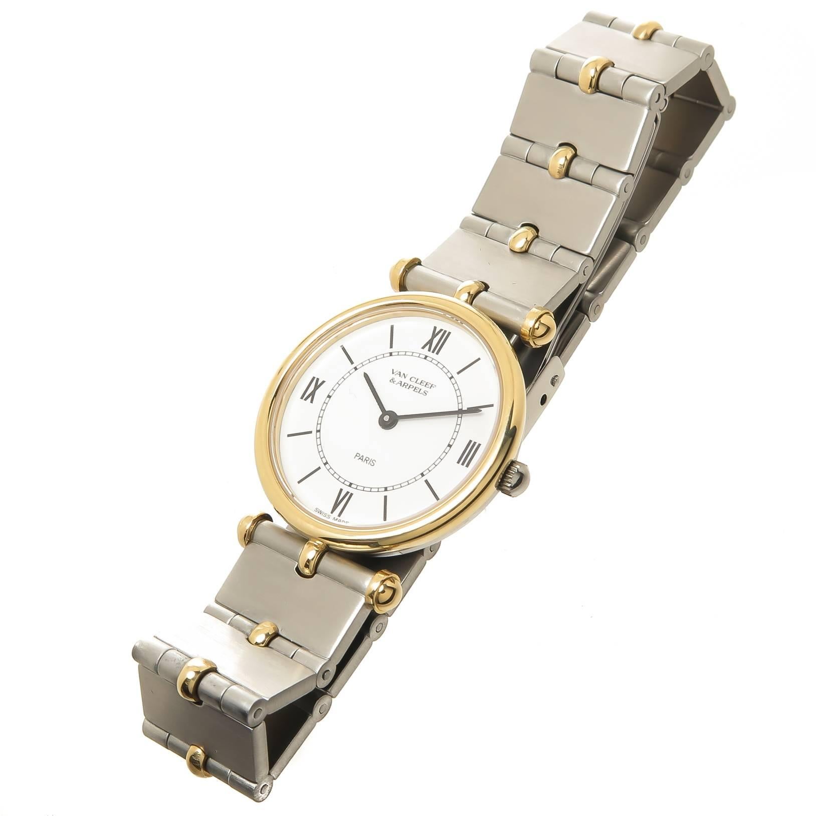 Circa 1990s Van Cleef and Arpels Ladies Wrist Watch. 24 MM Stainless Steel case with Yellow Gold Bezel, Quartz Movement, white Dial with Black Markers. 1/2 inch wide Stainless Steel and Yellow Gold Bracelet with fold over Deployment clasp. Total