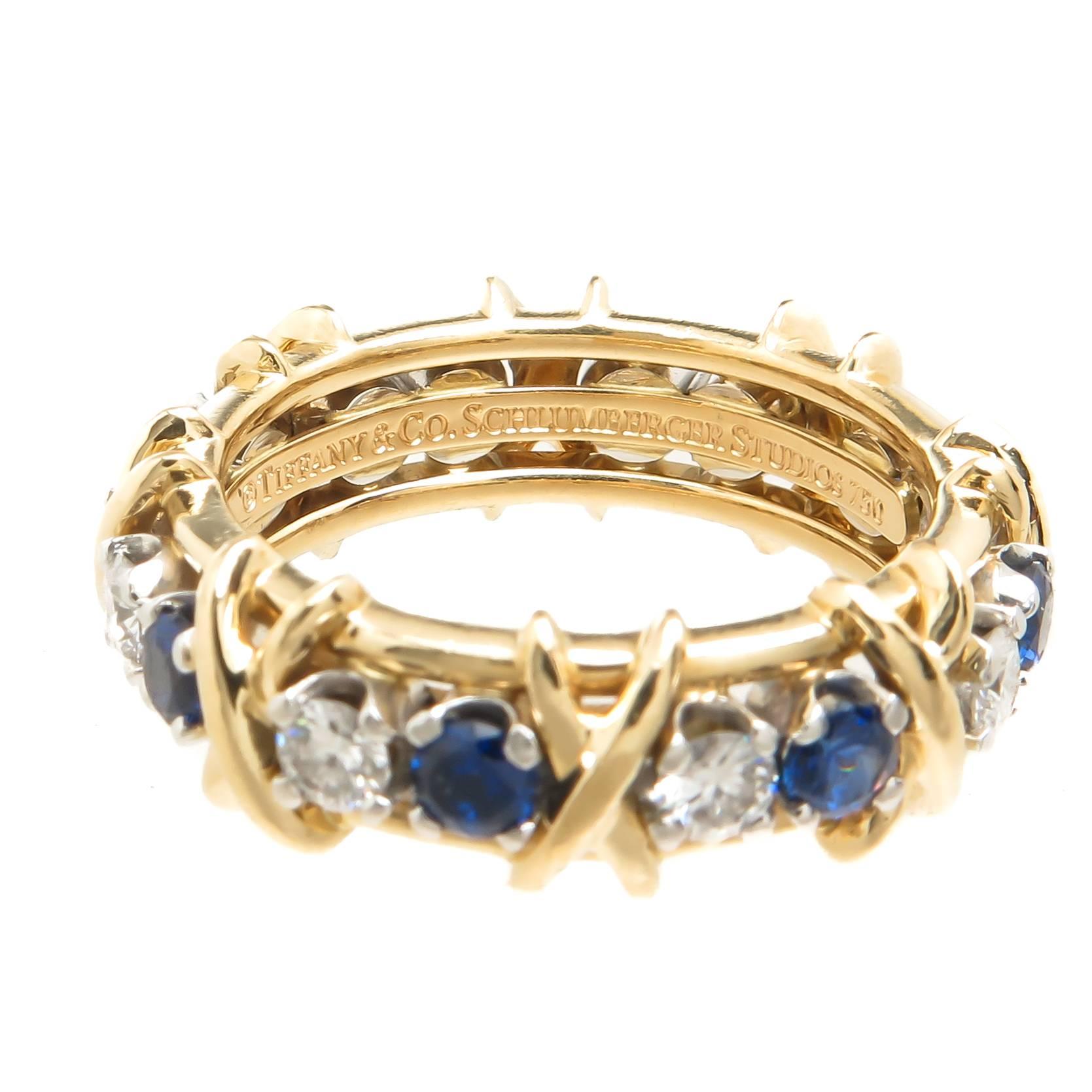Circa 2005 Jean Schlumberger for Tiffany & Company X Band Ring, 18K Yellow Gold and set with 8 Round Brilliant cut Diamonds Grading as G in color and VS in Clarity and 8 Fine Color sapphires. Measuring 5 MM wide and a finger size 6 1/2.