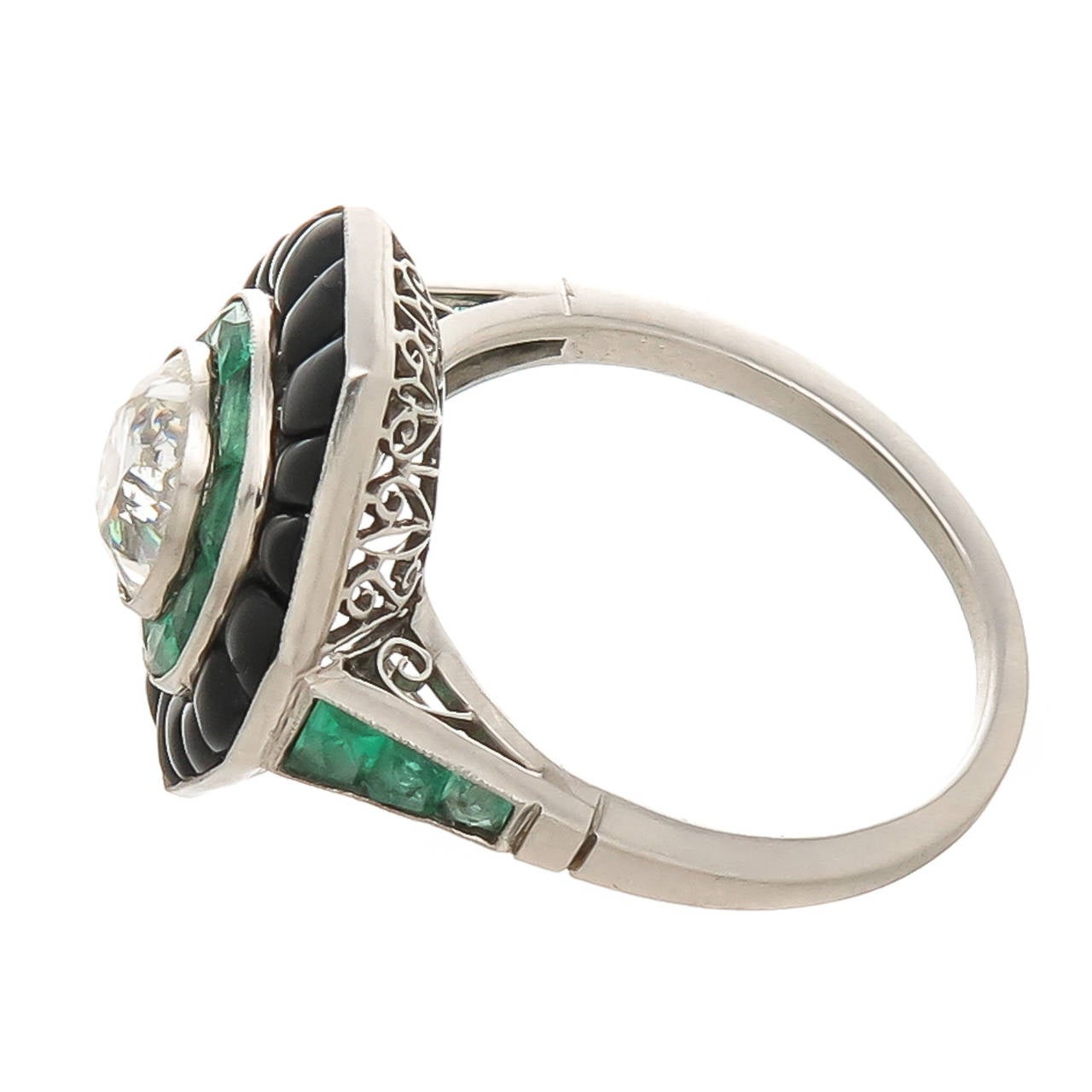 Finely Made late 20th Century  ring. Platinum and centrally set with an Old 1.30 Carat Cushion Cut Diamond grading as J-K in color and SI2 in Clarity. surrounded by Emeralds and Buff Cut Onyx. Fine Gallery work underneath. Absolutely looks and feels