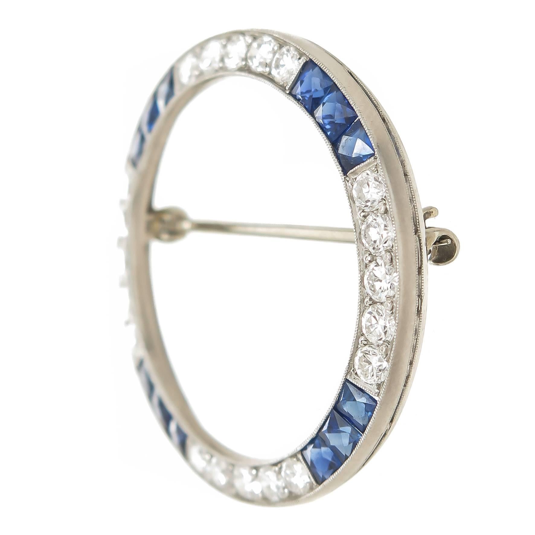 Circa 1960s Oscar Heyman Platinum Circle Brooch, set with Round Brilliant cut Diamonds totaling 1 Carat and Fine color French cut sapphires. The brooch measures 1 3/8 inch in diameter. 