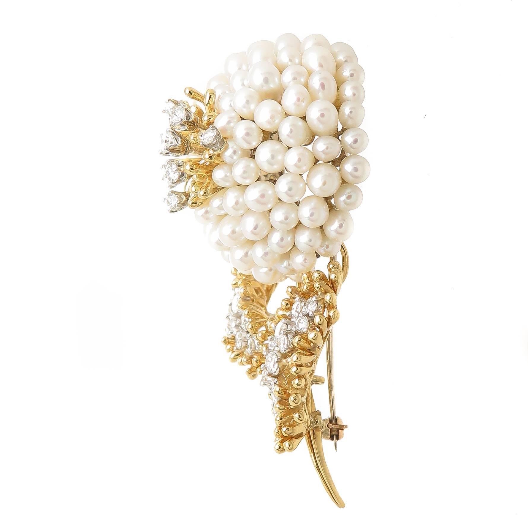 Circa 1980s Kurt Wayne 18K yellow Gold Flower Brooch, set with Round Brilliant cut Diamonds totaling 1.50 Carat and Grading as G in Color and VS in Clarity, further set with 3.5 MM Pearls. Measuring 2 5/8 inch in length.