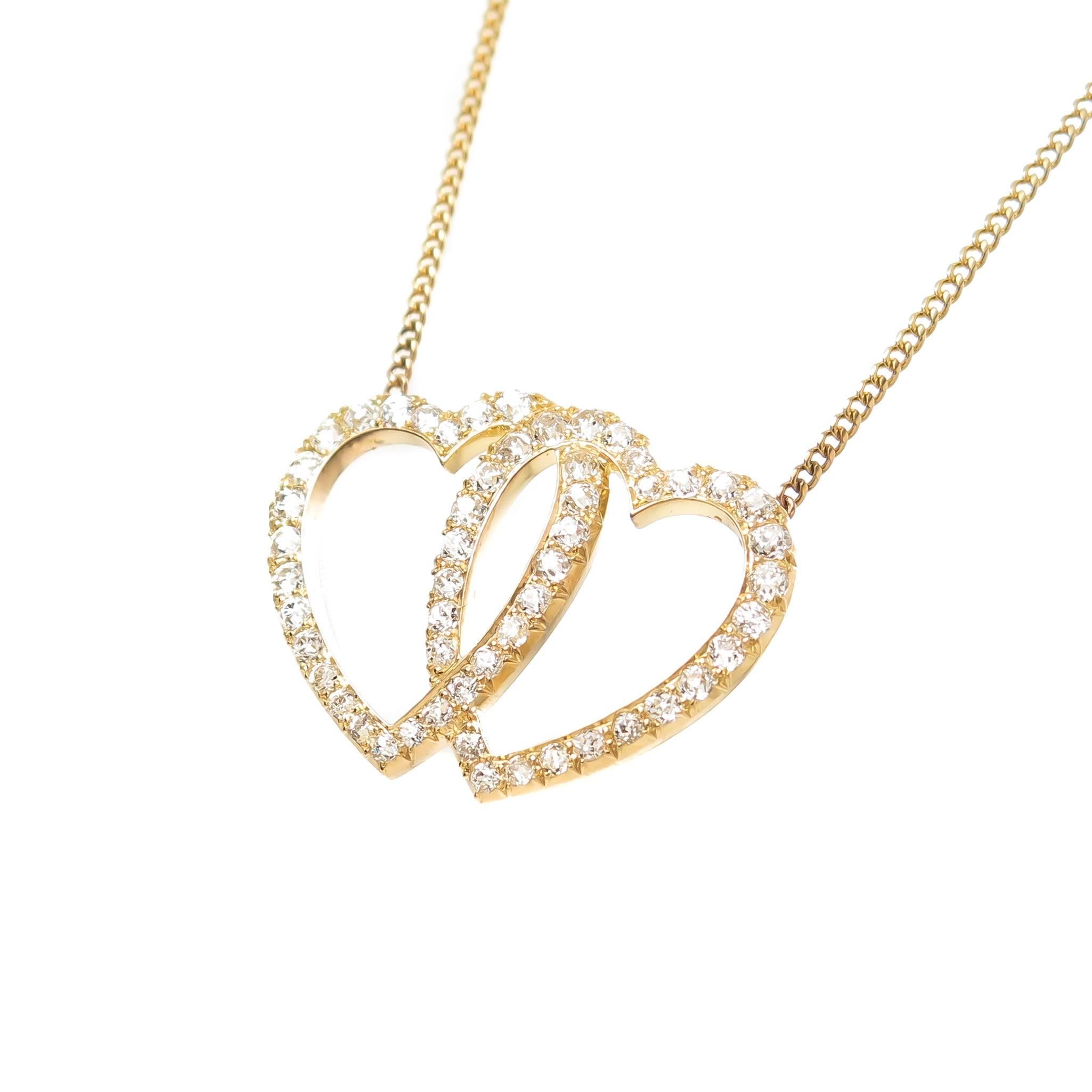 Circa 1900 Double Heart Pendant Necklace, 14K yellow Gold and set with old Mine Cut Diamonds that are very clean and White Grading as H in color and VS in Clarity and totaling 1.50 Carats. The hearts measure 1 3/16 inch X 7/8 inch and is attached to