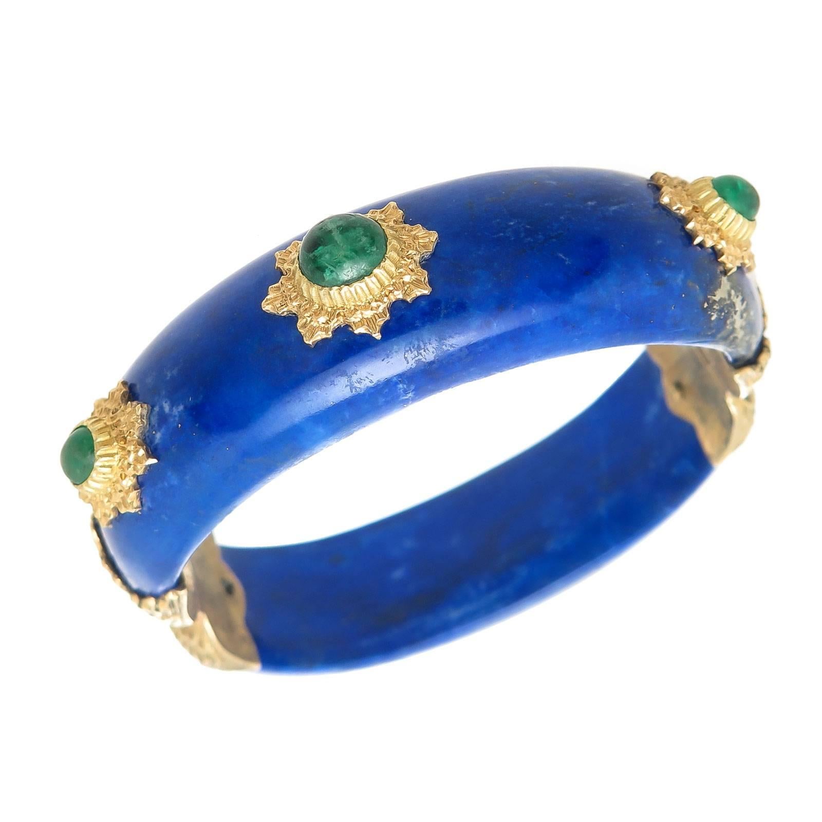 Circa 1970 Buccellati Lapis Lazuli Bangle Bracelet, with 18K yellow Gold Mounted Sections set with Cabochon Emeralds, the largest of which are approximately 1 Carat.  Measuring 5/8 inch wide,  3/8 inch thick and having an inside measurement of 6