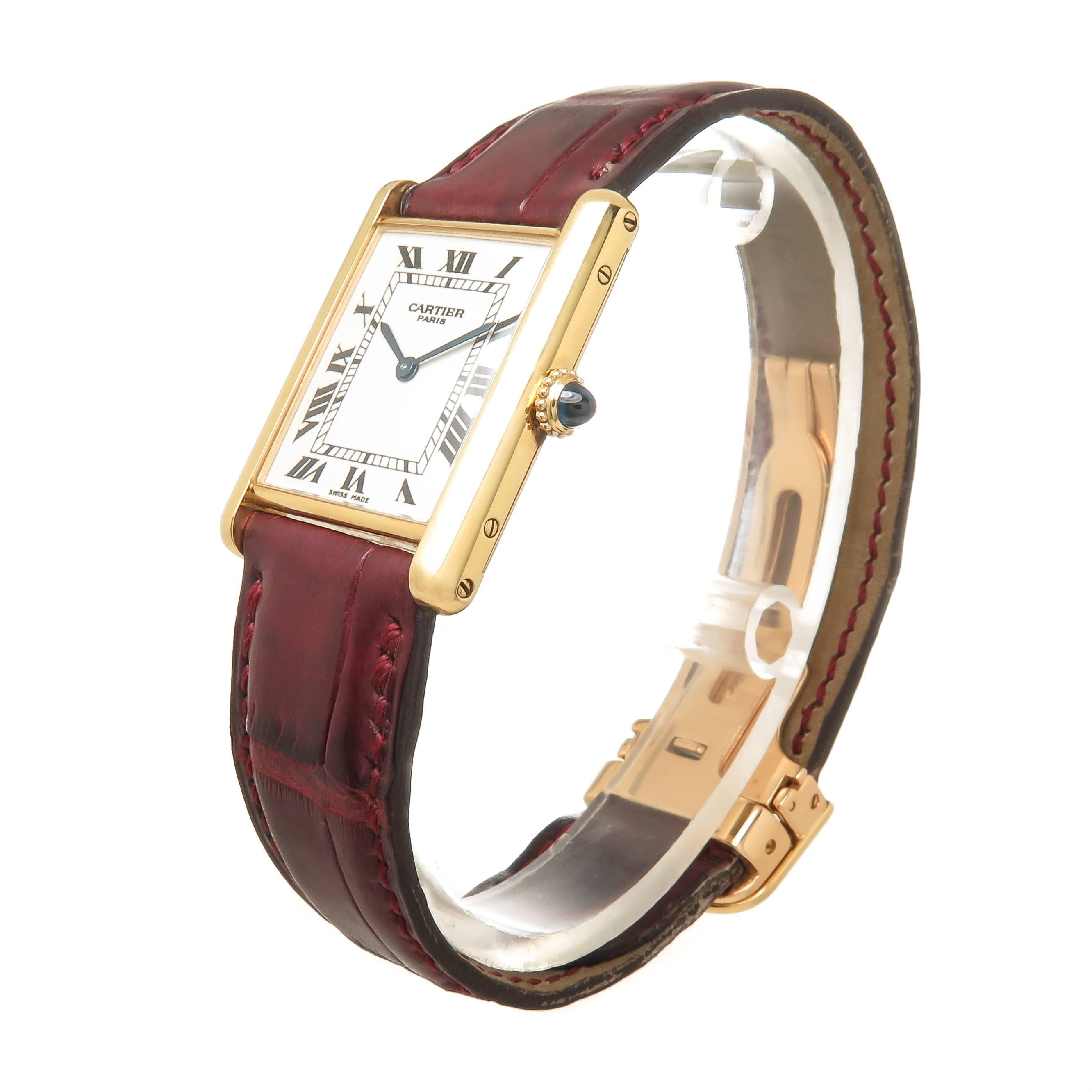 Circa 2000 Cartier Tank Wrist watch, 30 X 24 MM 18K Yellow Gold Case, Mechanical, Manual Wind movement, Engine Turned White Dial with Black Roman Numerals. 17.5 MM Cartier Burgundy Textured Grain adjustable Strap with 18K yellow Gold Cartier