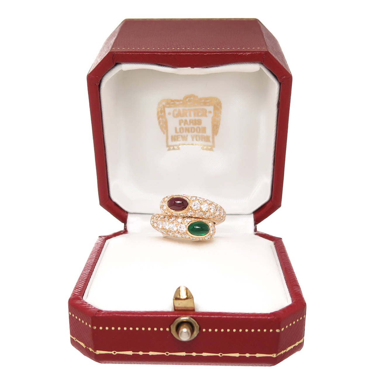 Circa 1990s Cartier 18k Yellow Gold Bypass Ring, centrally set with a very Fine Color Cabochon Ruby and Emerald, each approximately 3/4 Carat. Further set with Fine White Round Brilliant cut Diamonds totaling 2.50 Carats. Signed and Numbered.