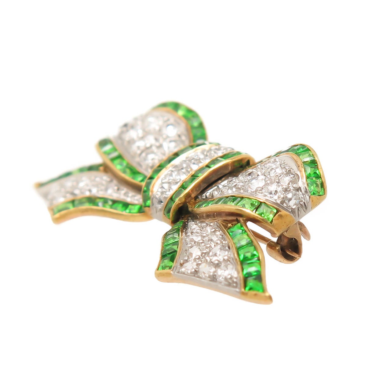 Edwardian 14K Yellow Gold and Platinum Bow Brooch, set with old mine cut diamonds that are white and clean and total 1.50 Carat. Further set with Square cut Green Demantoid Garnets that are of intense  bright Green color, most likely of Russian