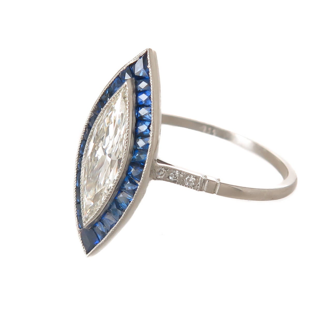 Platinum ring centrally set with a Marquise Diamond weighing .90 Carat that is J in Color and VS2 in Clarity, the diamond faces as or has the appearance of being a 1 carat stone. The Marquise is surrounded by French cut Natural Sapphires. with