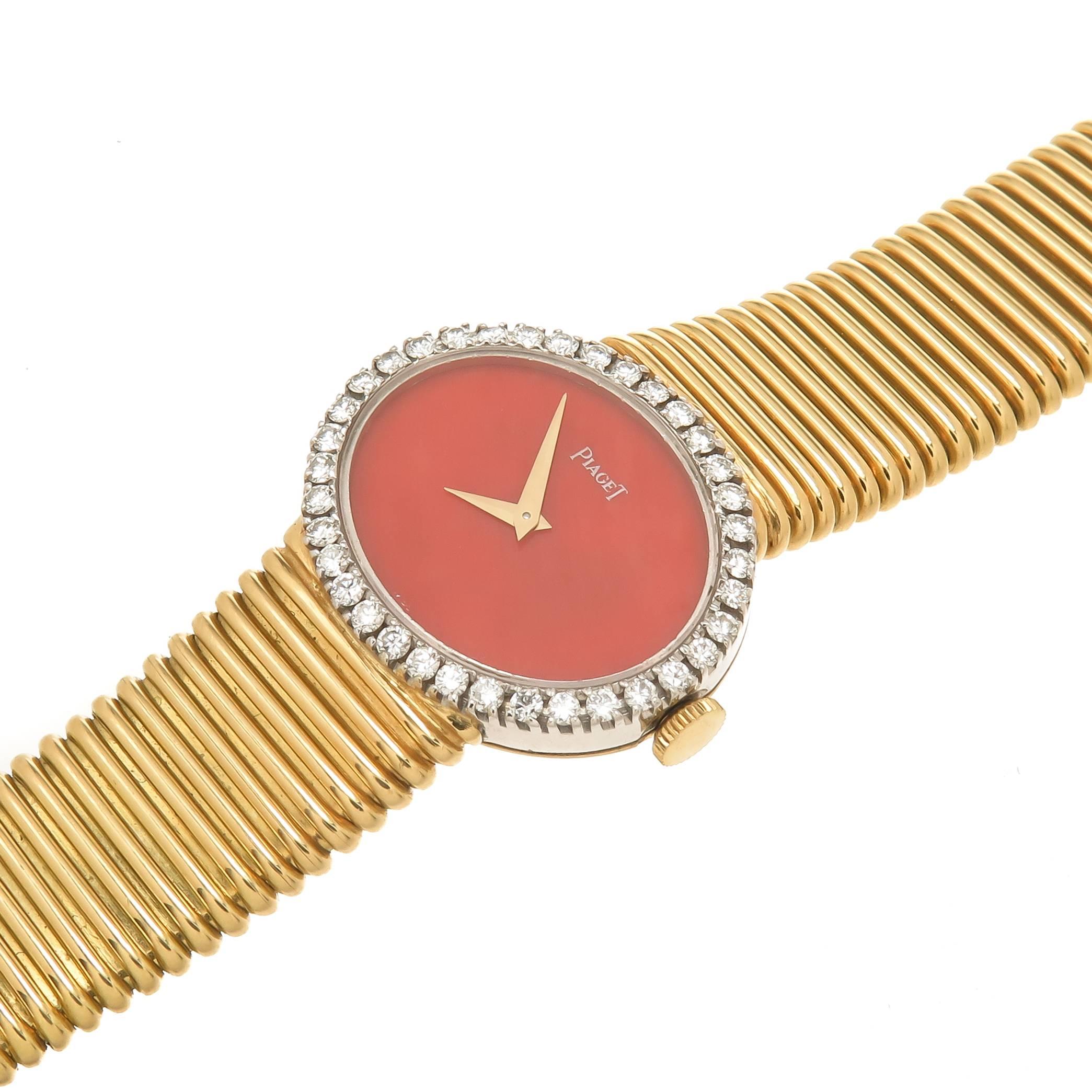 Circa 1970 Piaget 18K Yellow Gold Ladies Wrist Watch measuring 1 inch X 7/8 inch and attached to a flexible Bracelet measuring 5/8 inch wide, total length of watch 6 5/8 inch. 17 Jewel Manual wind Movement, Coral Dial and a bezel set with 36 Round
