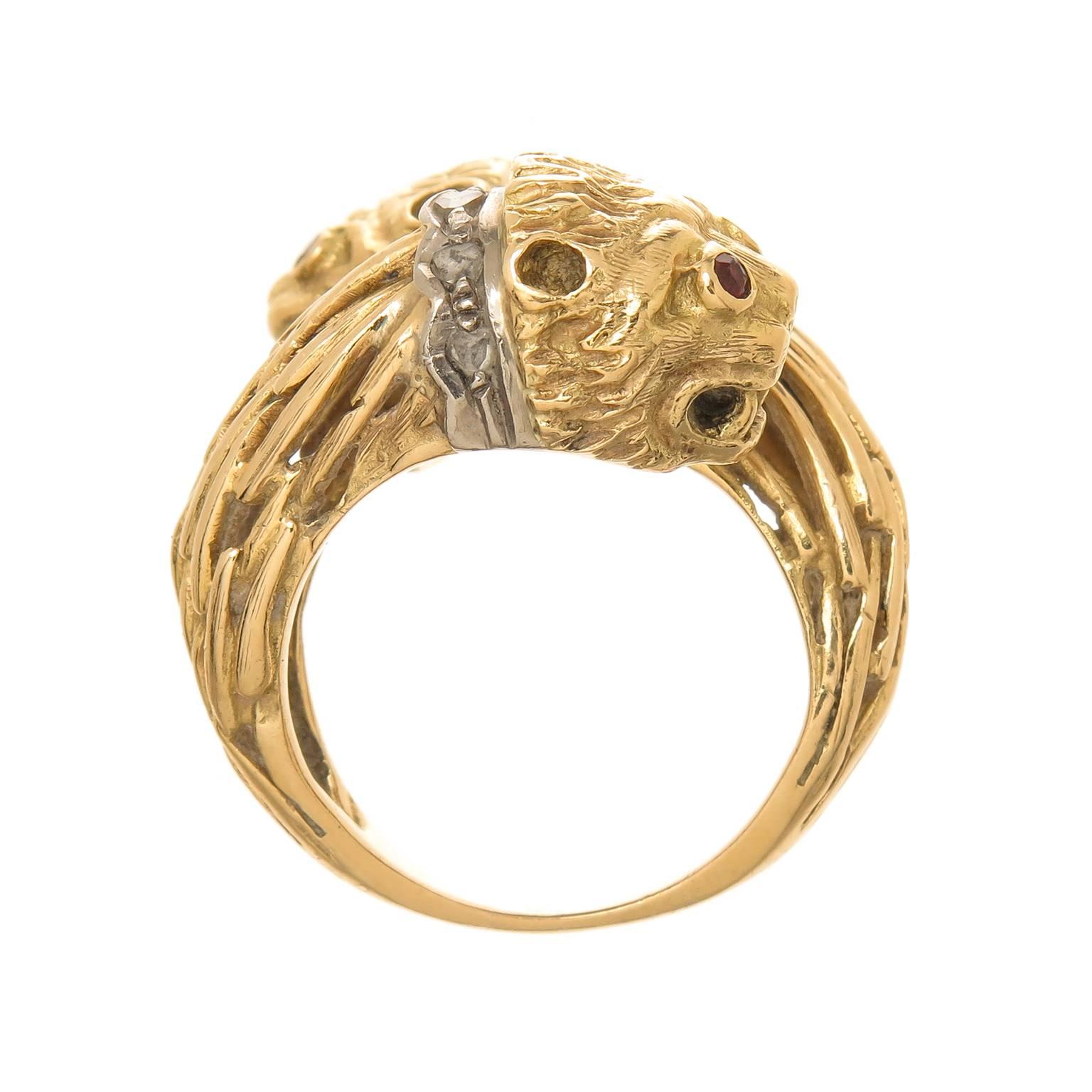 Circa 1970 Lalaounis 18K Yellow Gold Double Lion Head Bypass Ring, Hand textured and Having a White Gold Collar set with Diamonds and further accented with Ruby Eyes. Measuring 7/8 inch wide. Finger size = 6 1/2