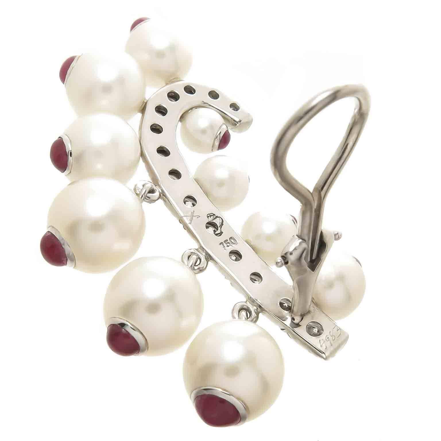 Circa 1960s Seaman schepps 18K White Gold Earrings, measuring 1 1/2 inch in length, set with Fine Cultured Pearls measuring in size from 8 to 3 MM and each has a Gold cap set with a Fine color Cabochon Ruby. Further set with Round Brilliant cut