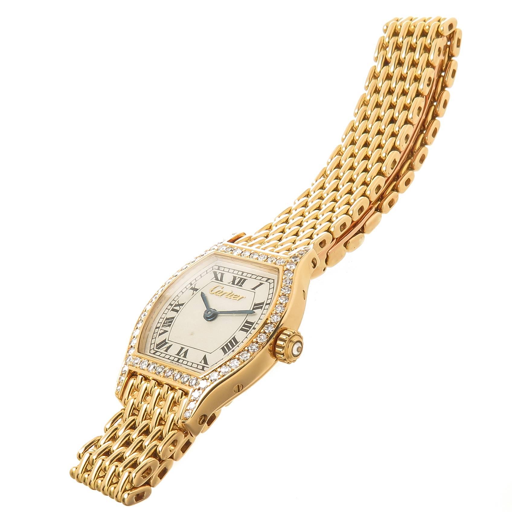 Circa 1990s Cartier Tortue Collection Ladies Wrist watch. 27 X 21 MM 18K yellow Gold Case with Cartier Factory set Diamond Bezel and Crown. Quartz Movement,  White Dial with Raised Gold Cartier logo and Black Roman numerals. 3/8 inch wide 18K Yellow