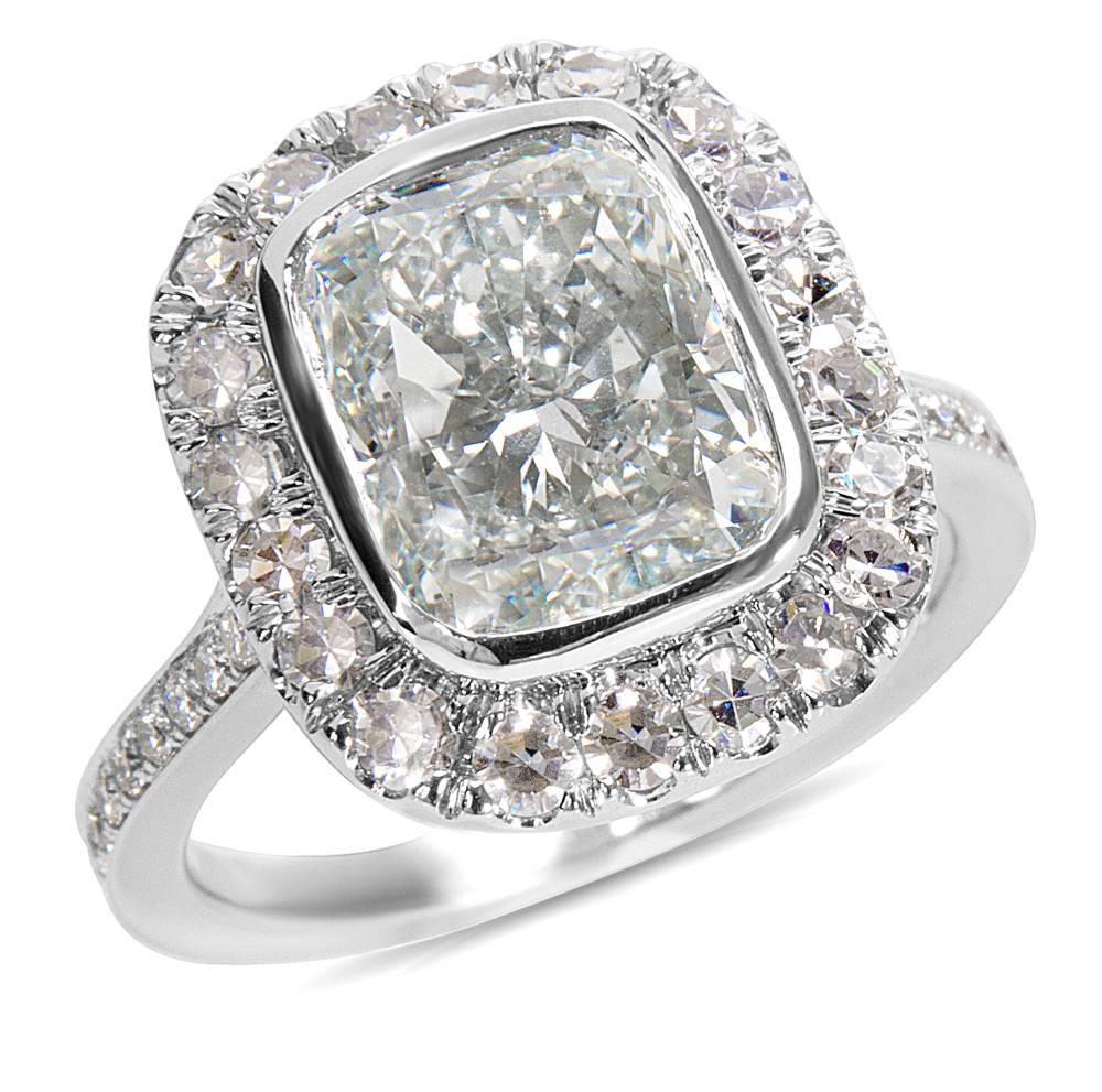 The center 4.06 carat cushion shaped diamond is F in color and VS1 in clarity. The additional 0.60 carats of diamonds in the halo setting are E-F in color and VS1 in clarity. This stunning diamond is set in 18K white gold. This piece, gleaming with