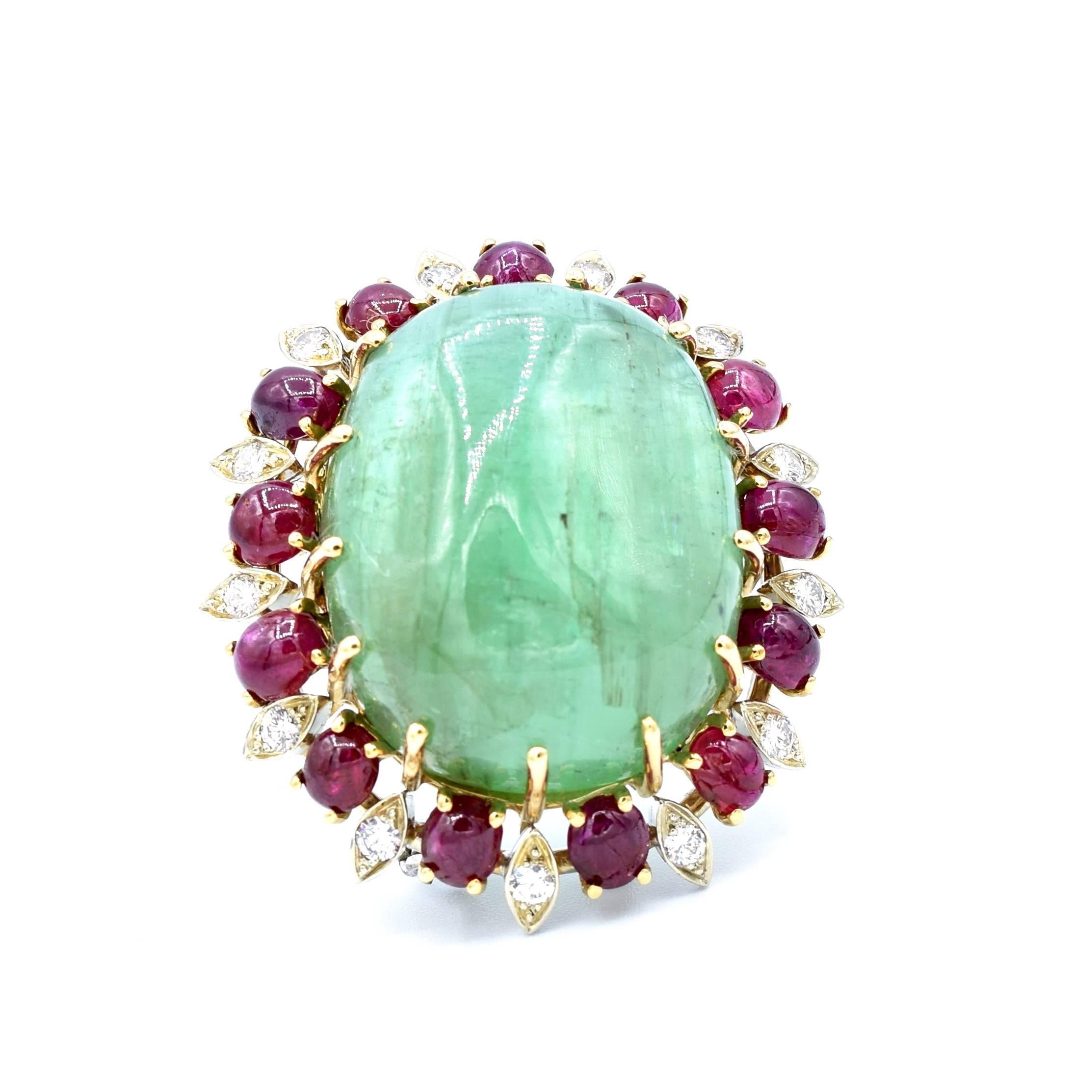 This well-crafted brooch is set with a cabochon-cut emerald (25.31x14.45mm), and is surrounded by 13 cabochon-cut rubies and by 13 round brilliant diamonds of approximately 0.65 total carat weight. 
