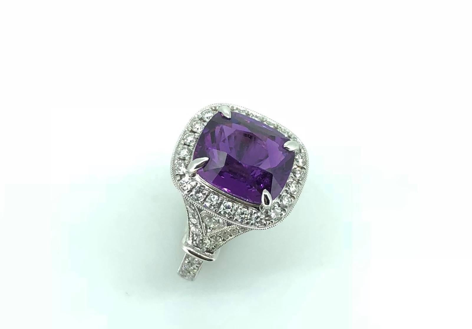 A Vivid Purple Sapphire Cushion cut 5.94 Carat Sapphire proudly sits upon an intricate milgrain-set cluster diamond ring. The vibrant and punchy vivid purple colour is not enhanced by any thermal heating, exhibiting a unique colour of sapphire. The