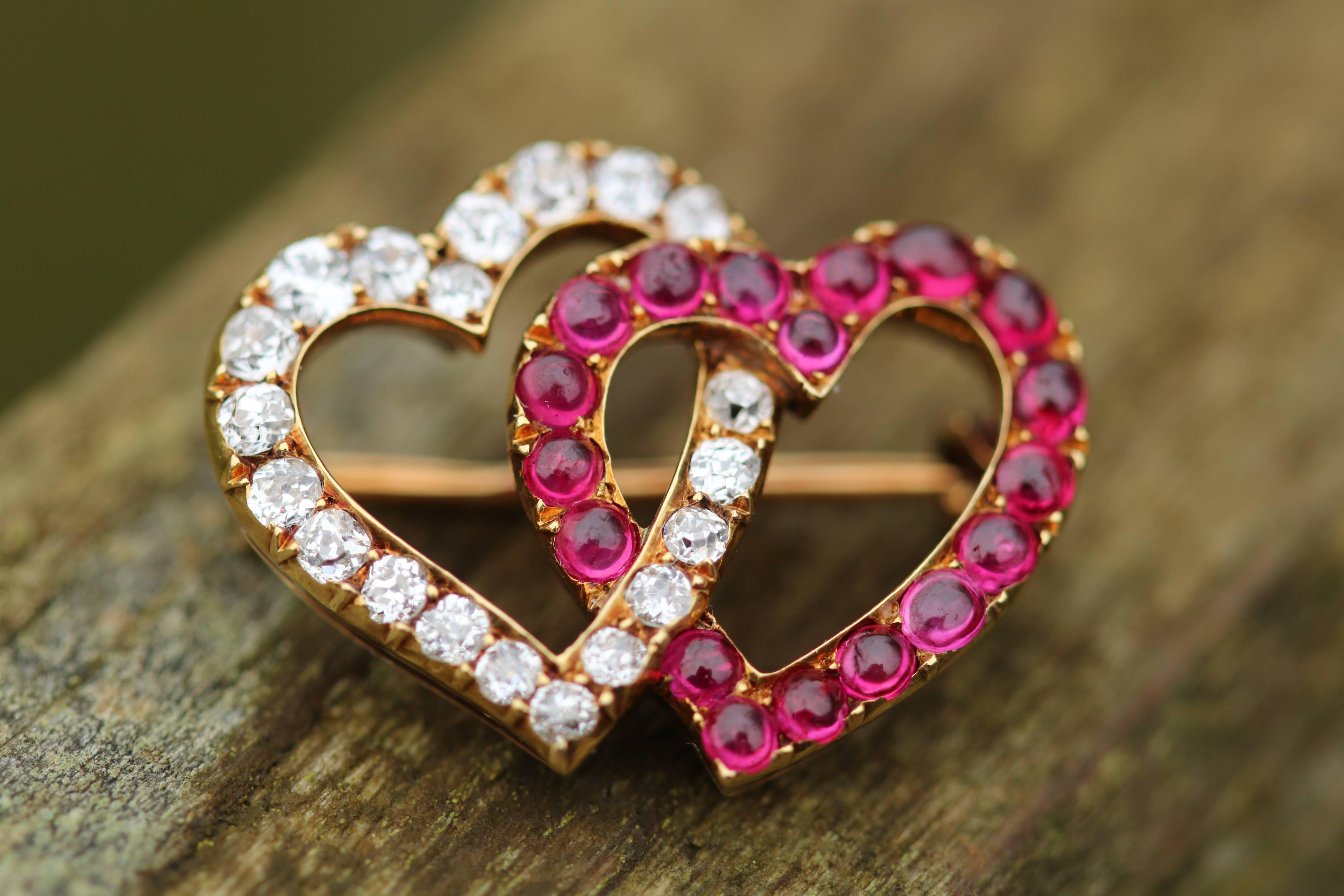 This is a beautiful and sweet brooch with two intertwined hearts; one made up of cabochon Burmese rubies, the other with diamonds. This design is simple but beautifully executed. The contracting colours suit each other perfectly with the pretty