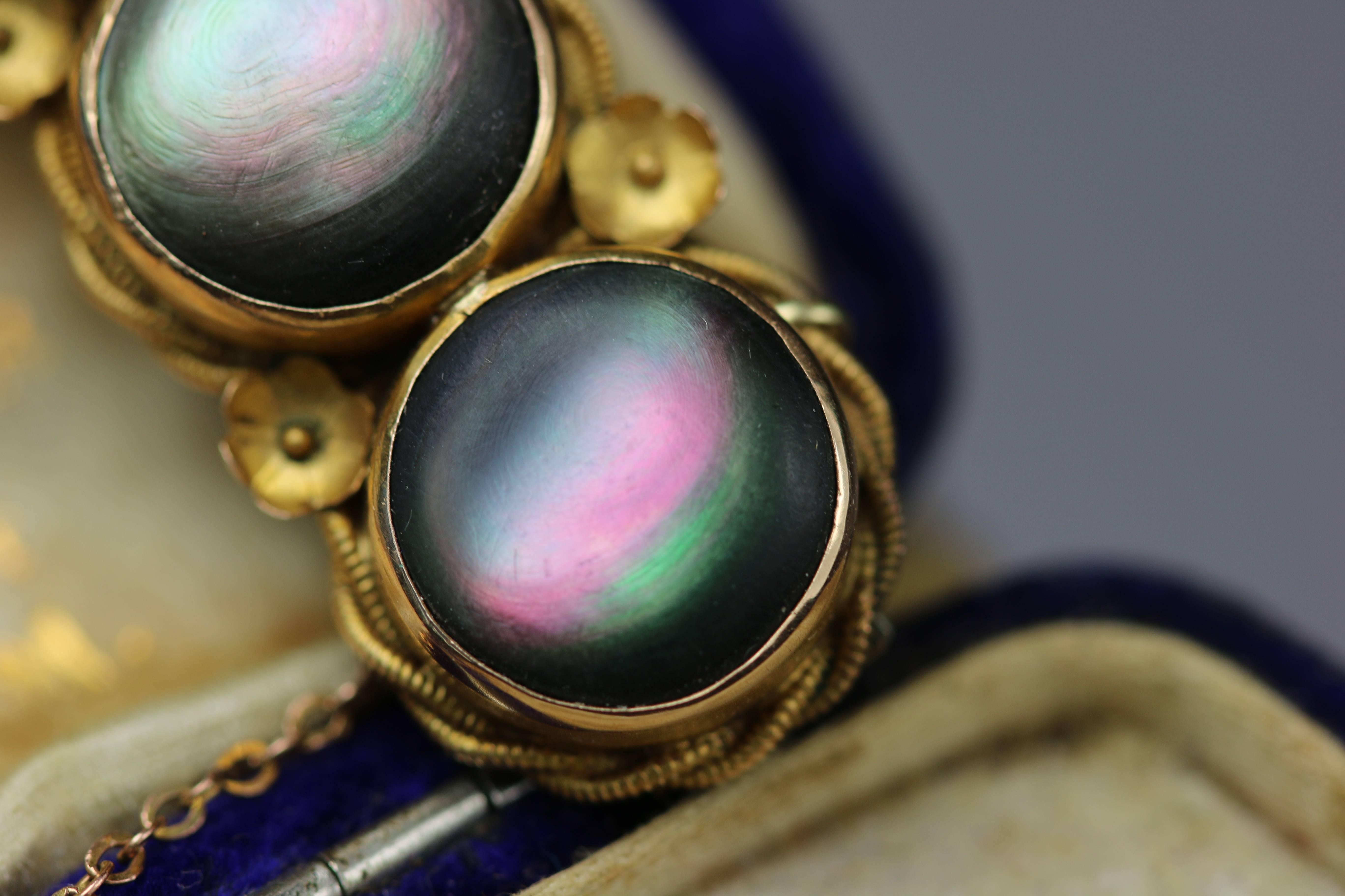 This is a wonderful example of Victorian jewellery. The main focus of the piece is the set of three mother of pearl discs. These have a beautiful dark body giving the perfect background to the colourful iridescence. The way the opalescent colours