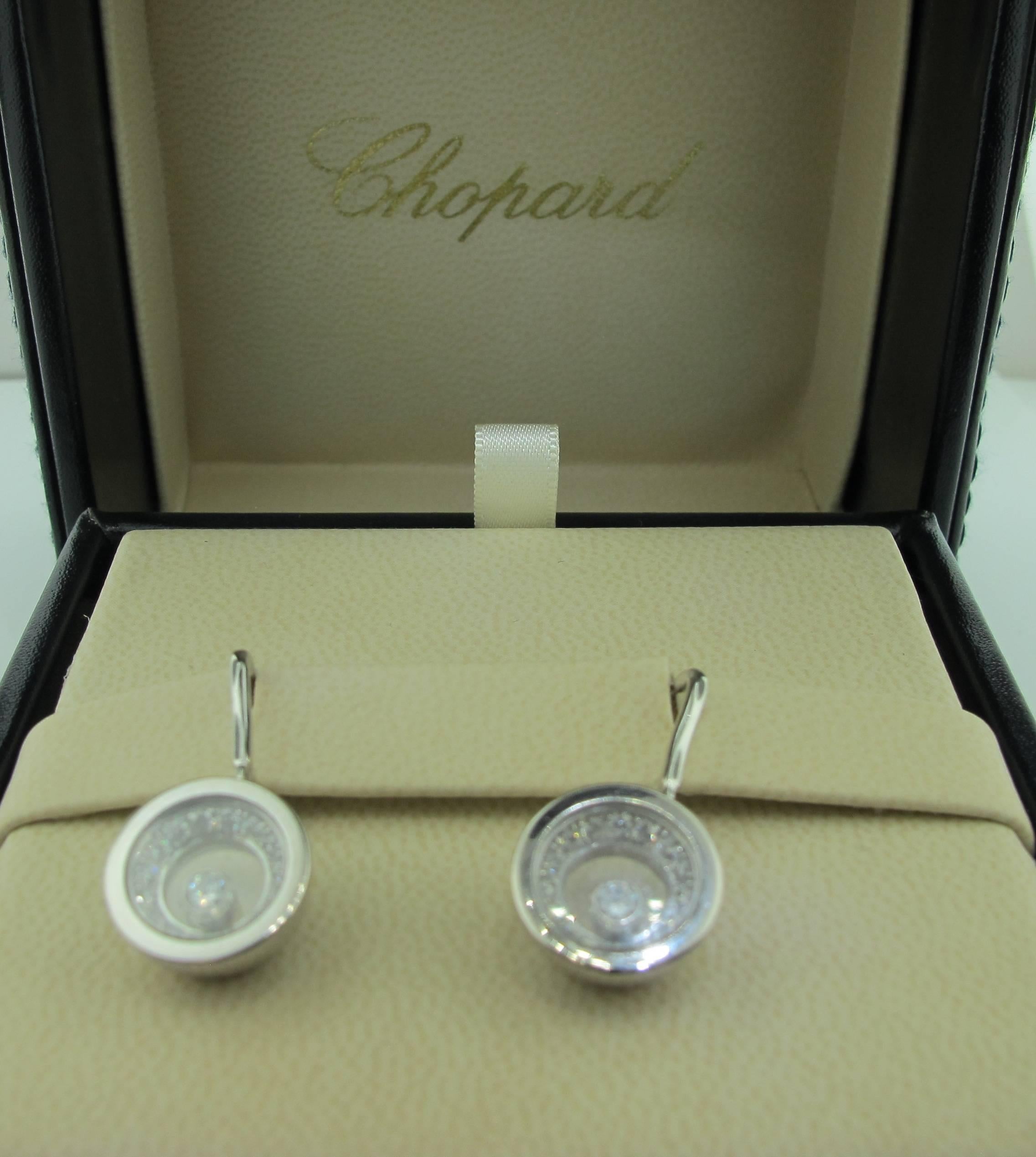 These Chopard Happy Diamond Earrings are signed and numbered.  They are set in 18 karat white gold weighing 11.8 grams.  There are 30 diamonds weighing 0.44 carats, plus the two "happy" diamonds that total 0.20 carats.  Color and clarity: