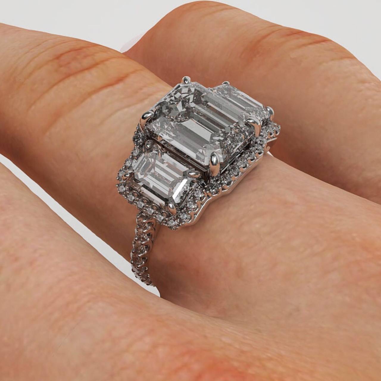 This exquisite 3 stone ring has been made to the exact measurements of the center diamond which boats a 4.00ct F color Vs1 clarity and flanked by two emerald cut diamonds by its side of 1.00ct each. We created the diamond halo without any gap at all