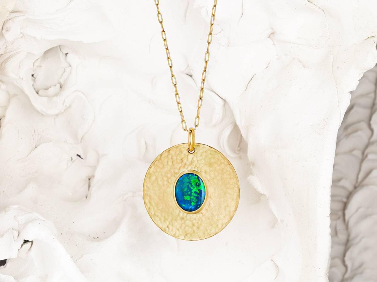 Substantial and Romanesque, this 18 and 22 karat hammered pendant boasts 16+ grams of reclaimed gold material to couch its stunning solid 2.06 ct Hopkins Australian Lightening Ridge opal. 
Thesis Gems and Jewelry creates fine jewelry with