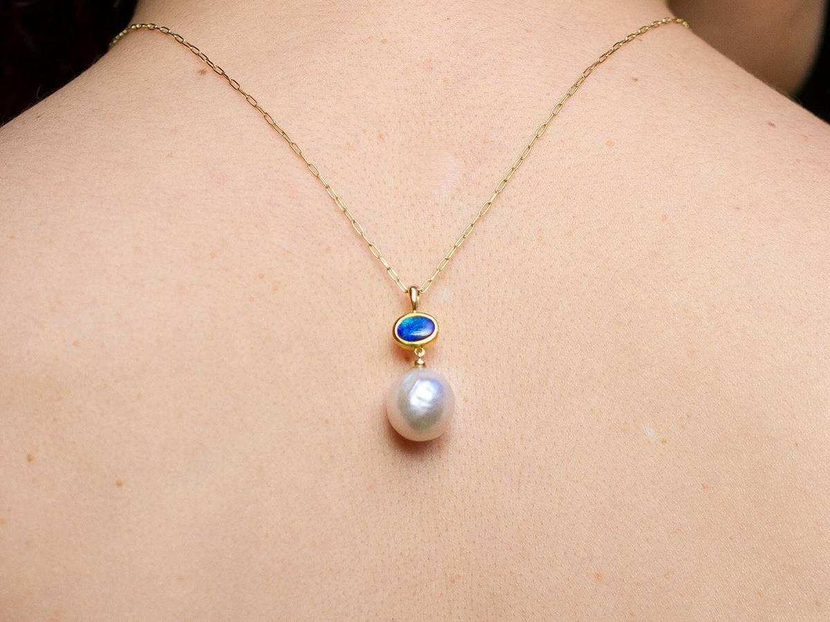 A 13 mm silver-violet Kasumi pearl and 0.5 carat solid Hopkins Australian opal unite vertically. 22 and 18 karat reclaimed gold setting. 
Thesis Gems and Jewelry creates fine jewelry with substantial, weighty gold fabrication. All gems and pearls