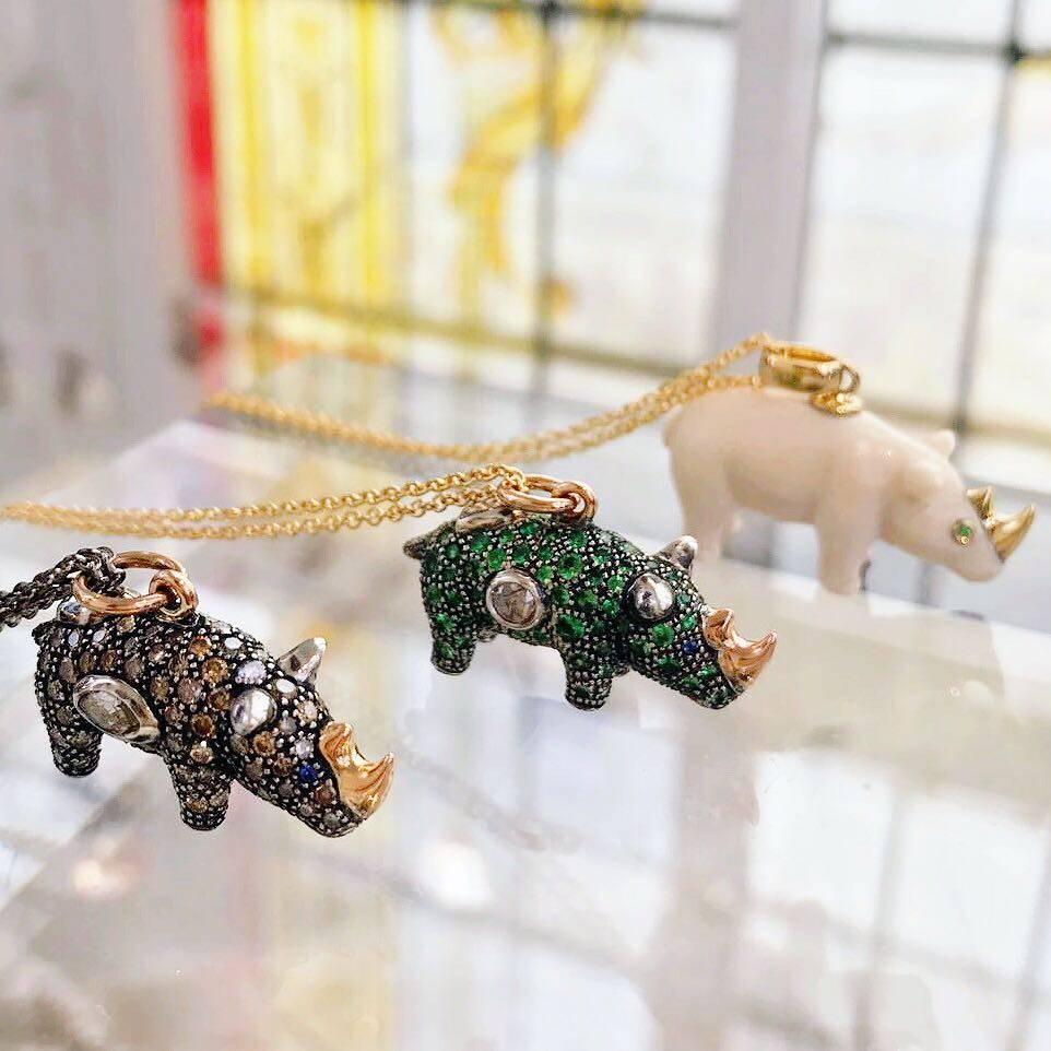 The Green Rhino Necklace, by Bibi van der Velden, is made of sterling silver fully-set with vibrant green Tsavorites and several rose-cut diamonds, with solid 18k rose gold accents and on an 18k rose gold chain. The rhino also features blue sapphire