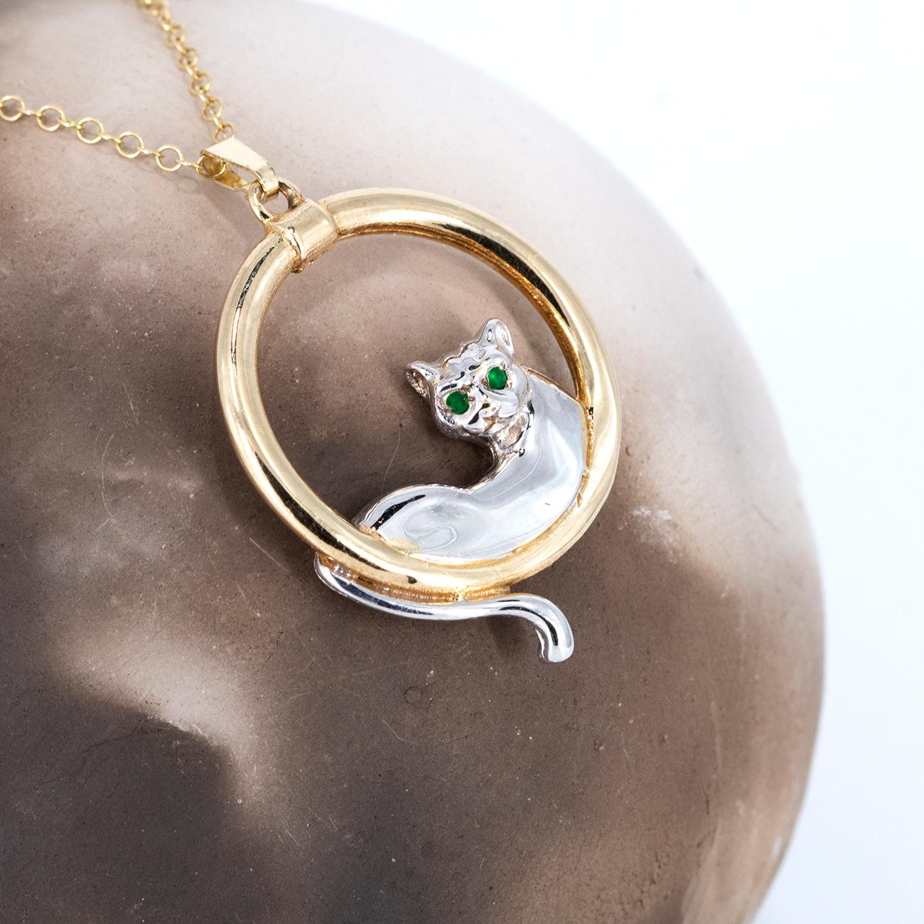 This languid cat is lying down , highlighted in white rhodium on top of the solid 9k gold. All cat lovers will identify with this sensuous feline at one with the world.
Simon has used a beautiful pair of emeralds as the eyes and the pendant is