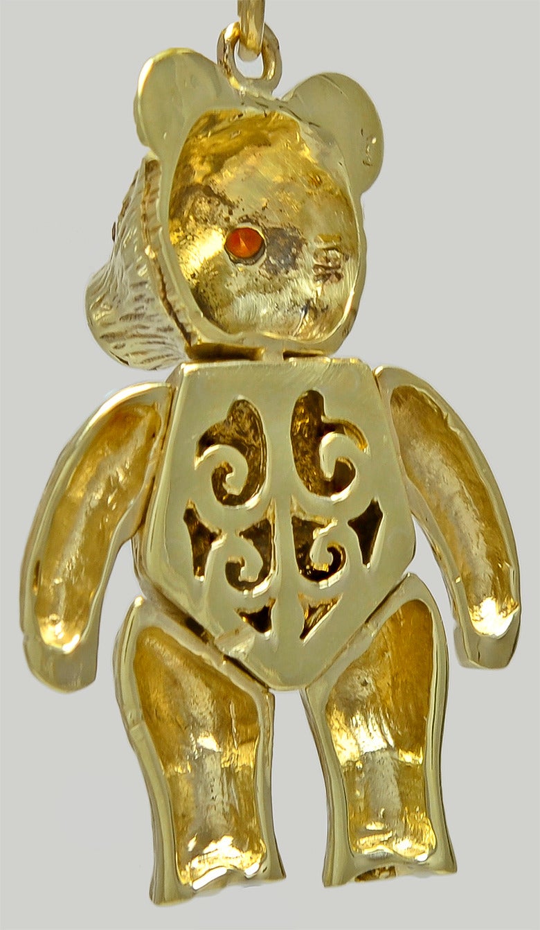 Figural Teddy Bear charm, with articulated arms and legs. Textured 14k
gold body, set with faceted ruby eyes. 1 1/3