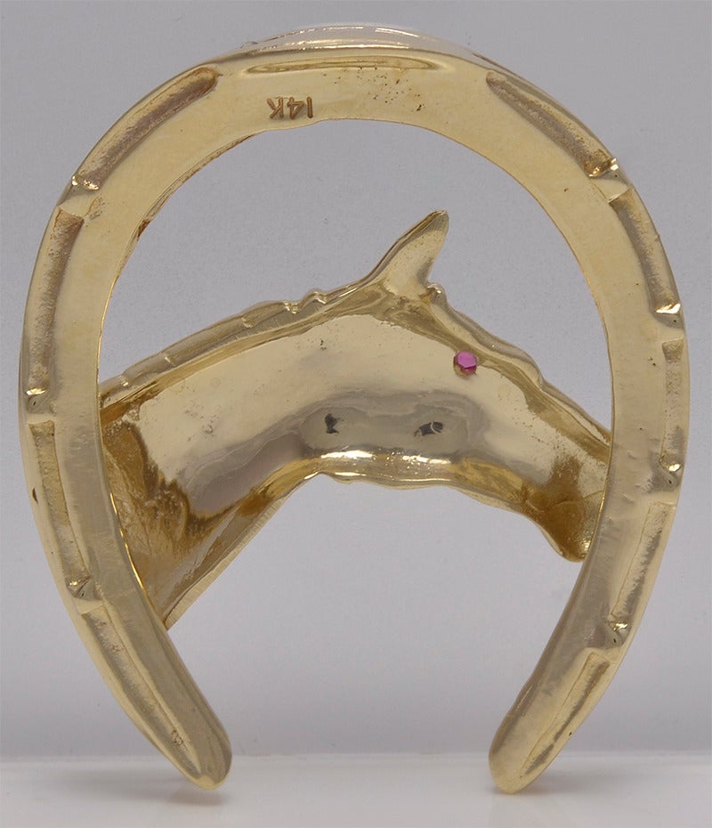 Large figural horse and horseshoe brooch.   Set in 14K yellow gold with faceted ruby eye.  2