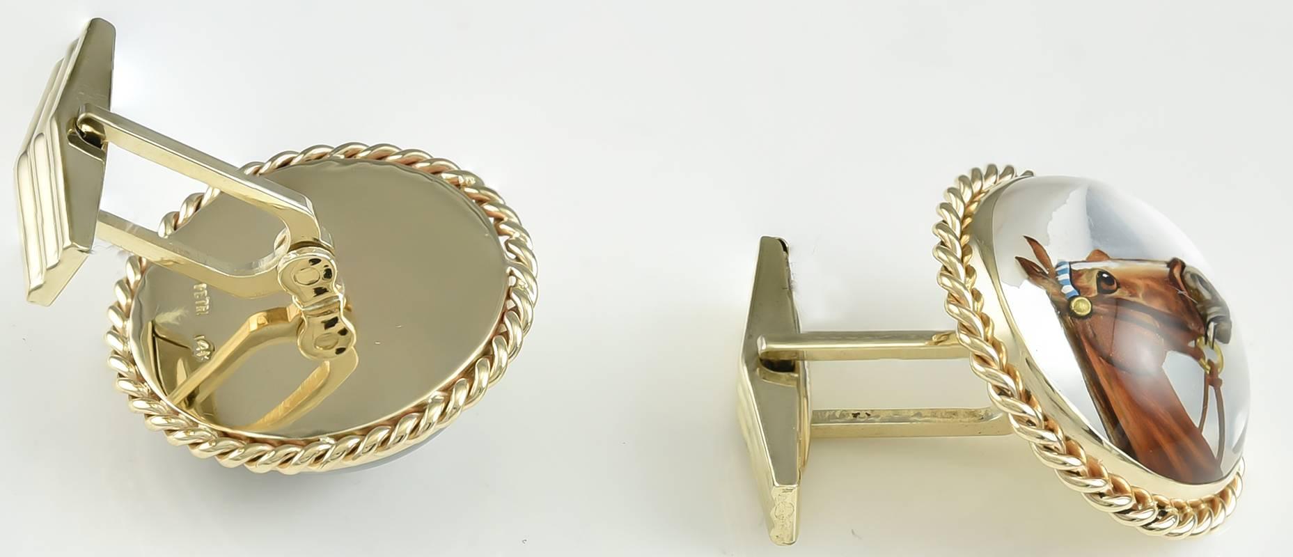 Large round reverse crystal cufflinks, showing a chestnut horse with a white stripe down his nose, and a blue and white trimmed bridle.  14K yellow gold, with an applied rope border.  Approximately 1