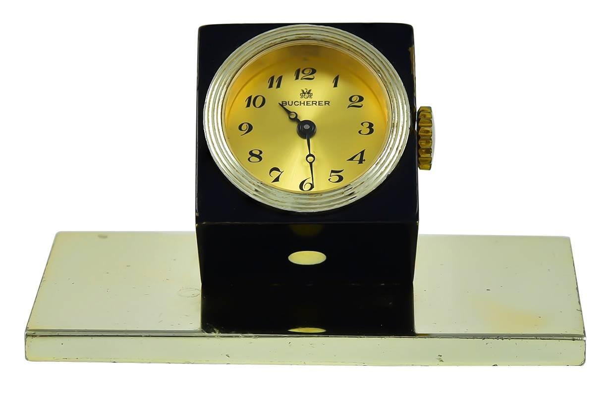Charming mini-clock:  a black and white enamel figural die, on a steel base,  Made and signed by BUCHERER.  Mechanical movement.  The die cube is 1