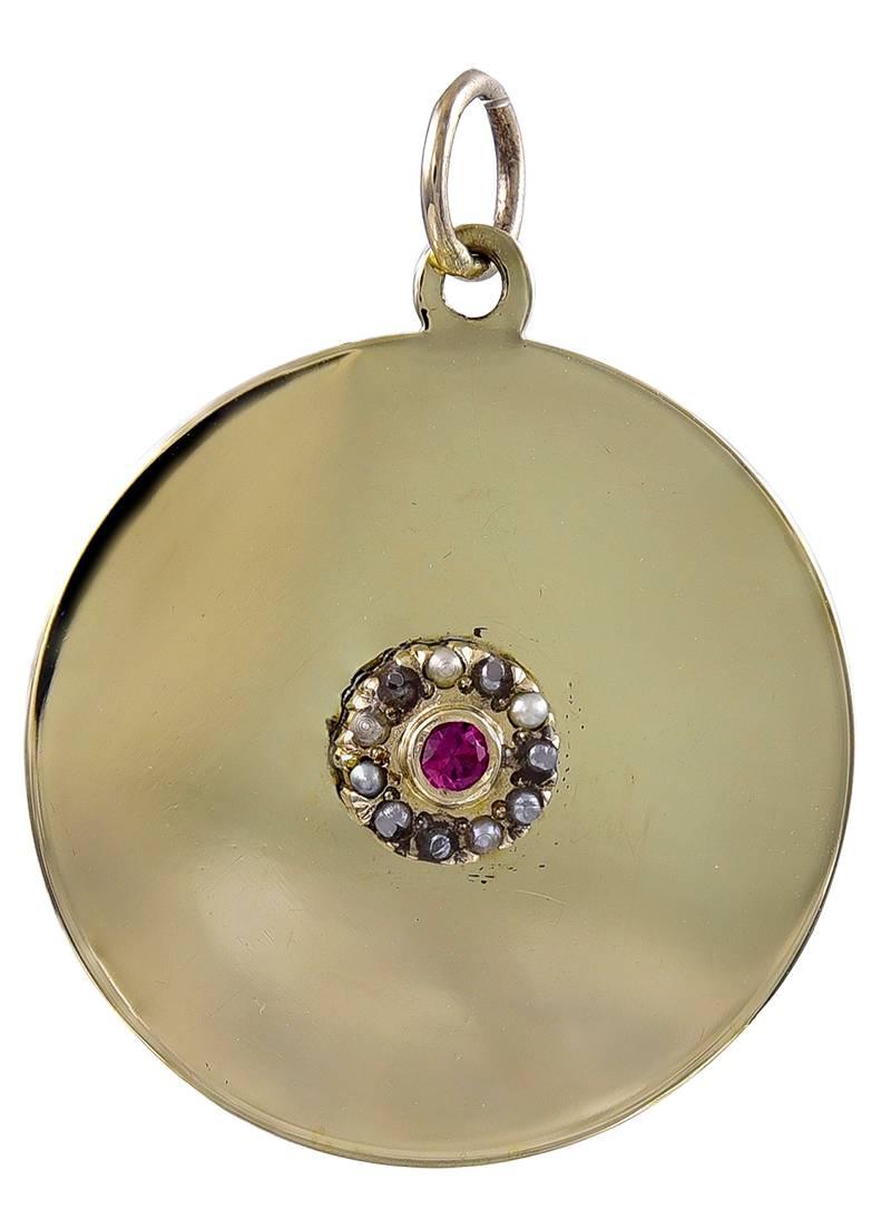 Round gold mellow yellow charm, with an applied center medallion:  a faceted bezel-set ruby surrounded by seed pearls.  1" in diameter.  For the "July" baby in your life.

Alice Kwartler has sold the finest antique gold and diamond