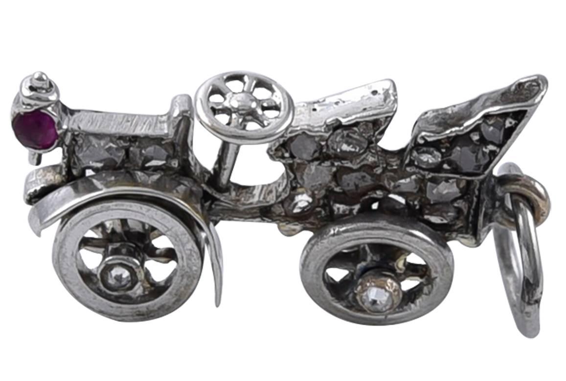 Figural "antique car" charm.  Platinum; set with rose-cut diamonds and a ruby.  The wheels spin around.  2/3" x 1/3."  

Alice Kwartler has sold the finest antique gold and diamond jewelry and silver for over forty years.